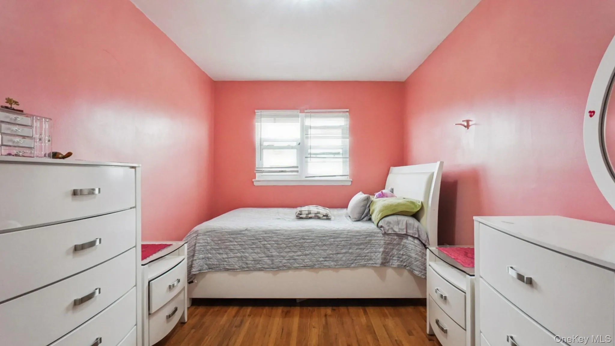 Bedroom featuring wood-finish flooring, a double window with blinds, and a flush-mount ceiling light Bedroom featuring wood-finish flooring, a double window with blinds, and a flush-mount ceiling light