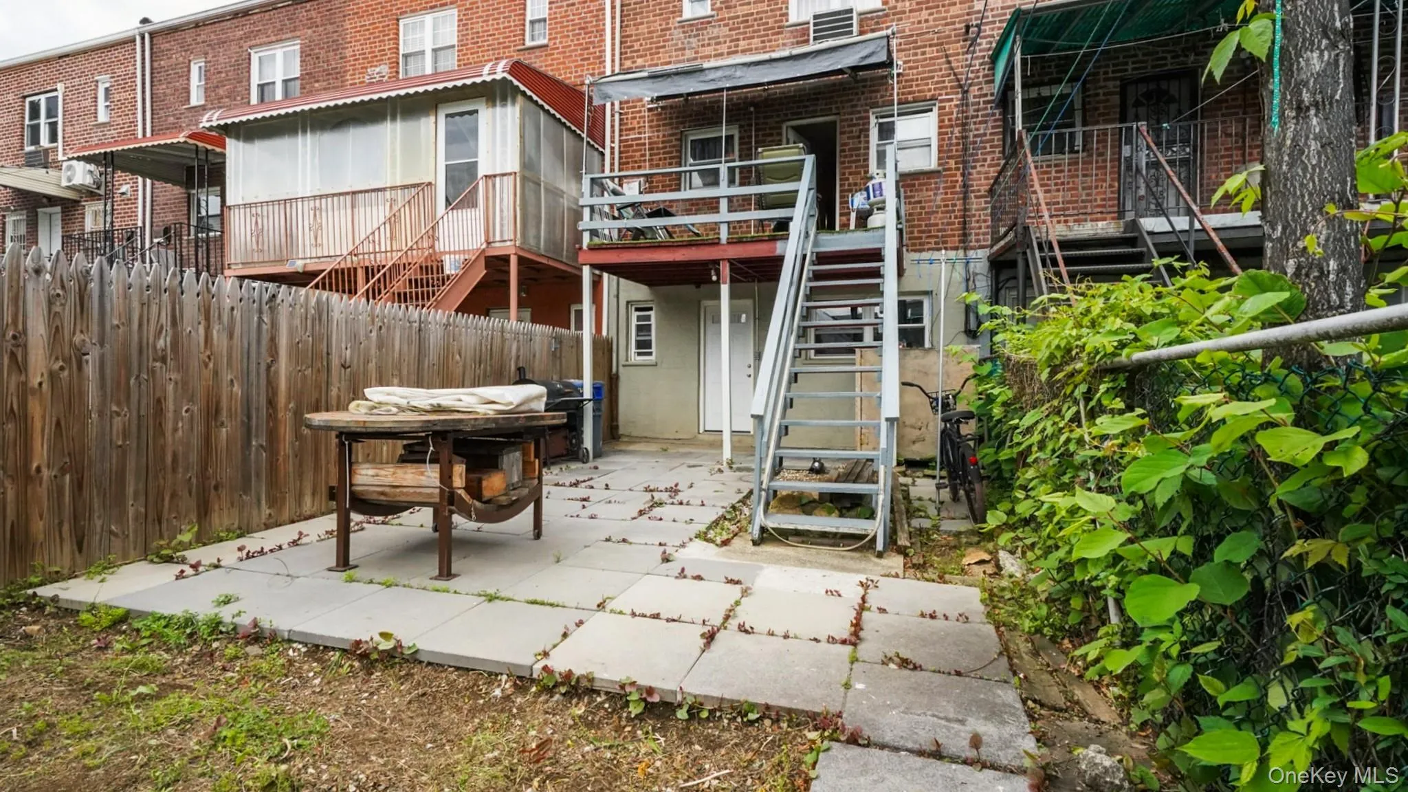 Rear exterior featuring a paver patio, wood privacy fence, and multi-level outdoor access stairs Rear exterior featuring a paver patio, wood privacy fence, and multi-level outdoor access stairs