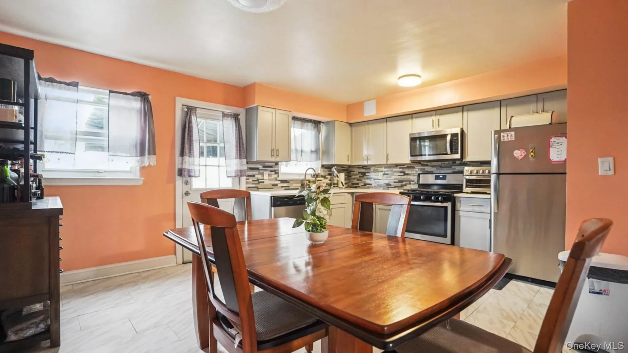 Kitchen featuring light grey cabinetry, stainless steel appliances, and a geometric tile backsplash Kitchen featuring light grey cabinetry, stainless steel appliances, and a geometric tile backsplash