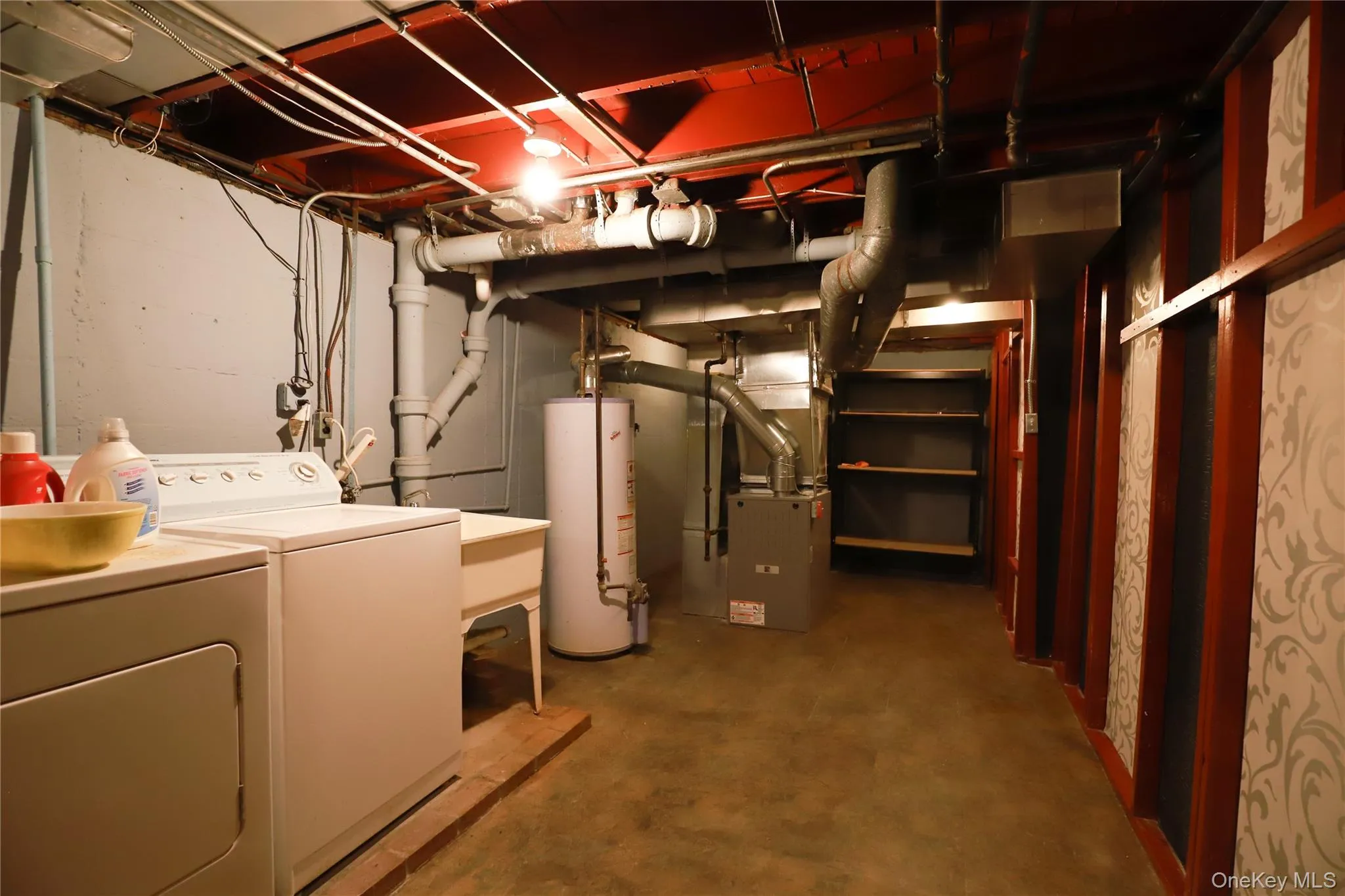 Basement utility area featuring a washer and dryer, laundry sink, and water heater Basement utility area featuring a washer and dryer, laundry sink, and water heater