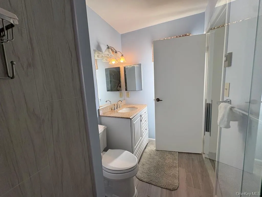 Primary bathroom featuring a white vanity with a stone countertop, dual-handle faucet, and an integrated sink Primary bathroom featuring a white vanity with a stone countertop, dual-handle faucet, and an integrated sink