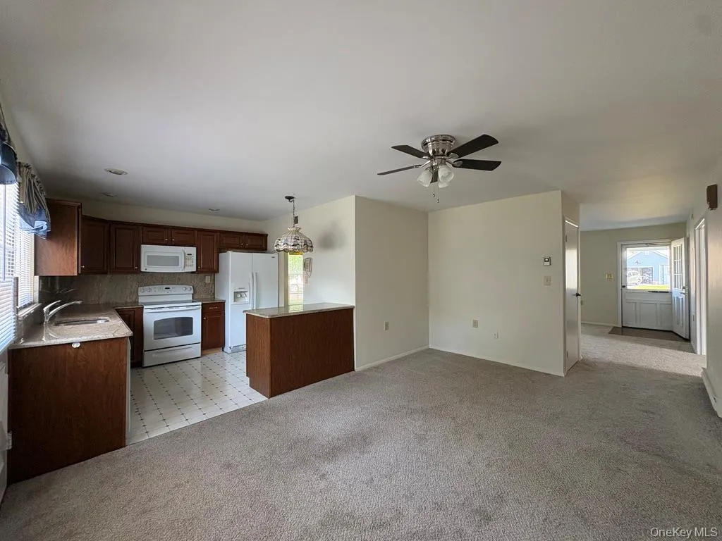 Open-concept living area featuring kitchen with light-toned granite countertops and a tile backsplash. Open-concept living area featuring kitchen with light-toned granite countertops and a tile backsplash.