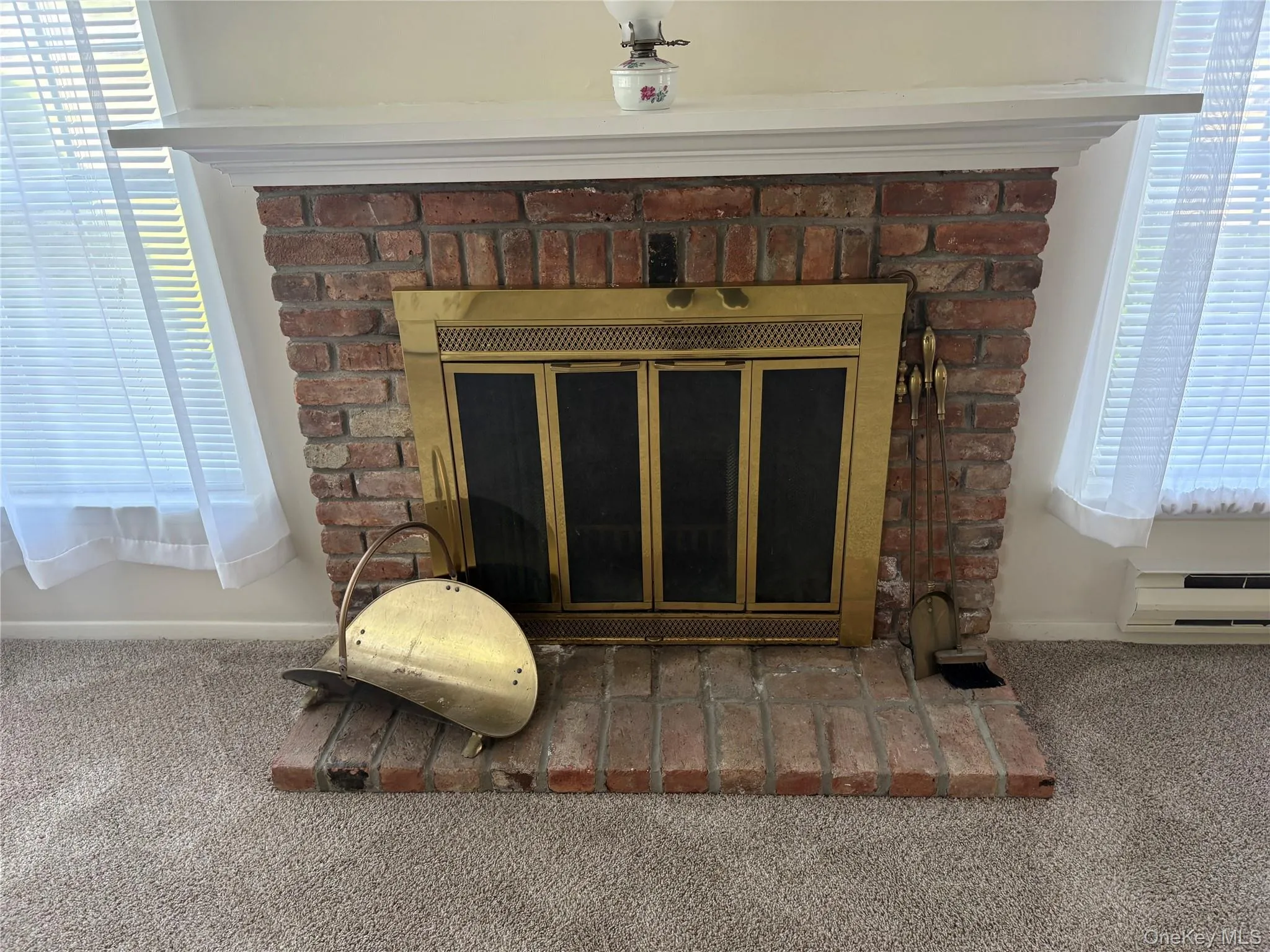 Wood burning fireplace with a brass fire screen and a white mantelpiece warms the heart and soul. Wood burning fireplace with a brass fire screen and a white mantelpiece warms the heart and soul.
