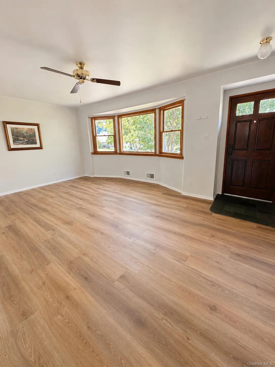 Interior Family room featuring wood-finish flooring, a bay window with natural wood trim, and a ceiling fan Interior Family room featuring wood-finish flooring, a bay window with natural wood trim, and a ceiling fan
