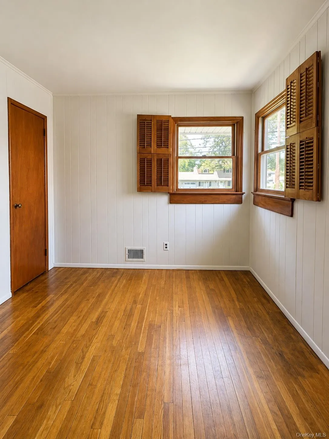 Bedroom 3, hardwood flooring complements vertical paneling and white trim Bedroom 3, hardwood flooring complements vertical paneling and white trim