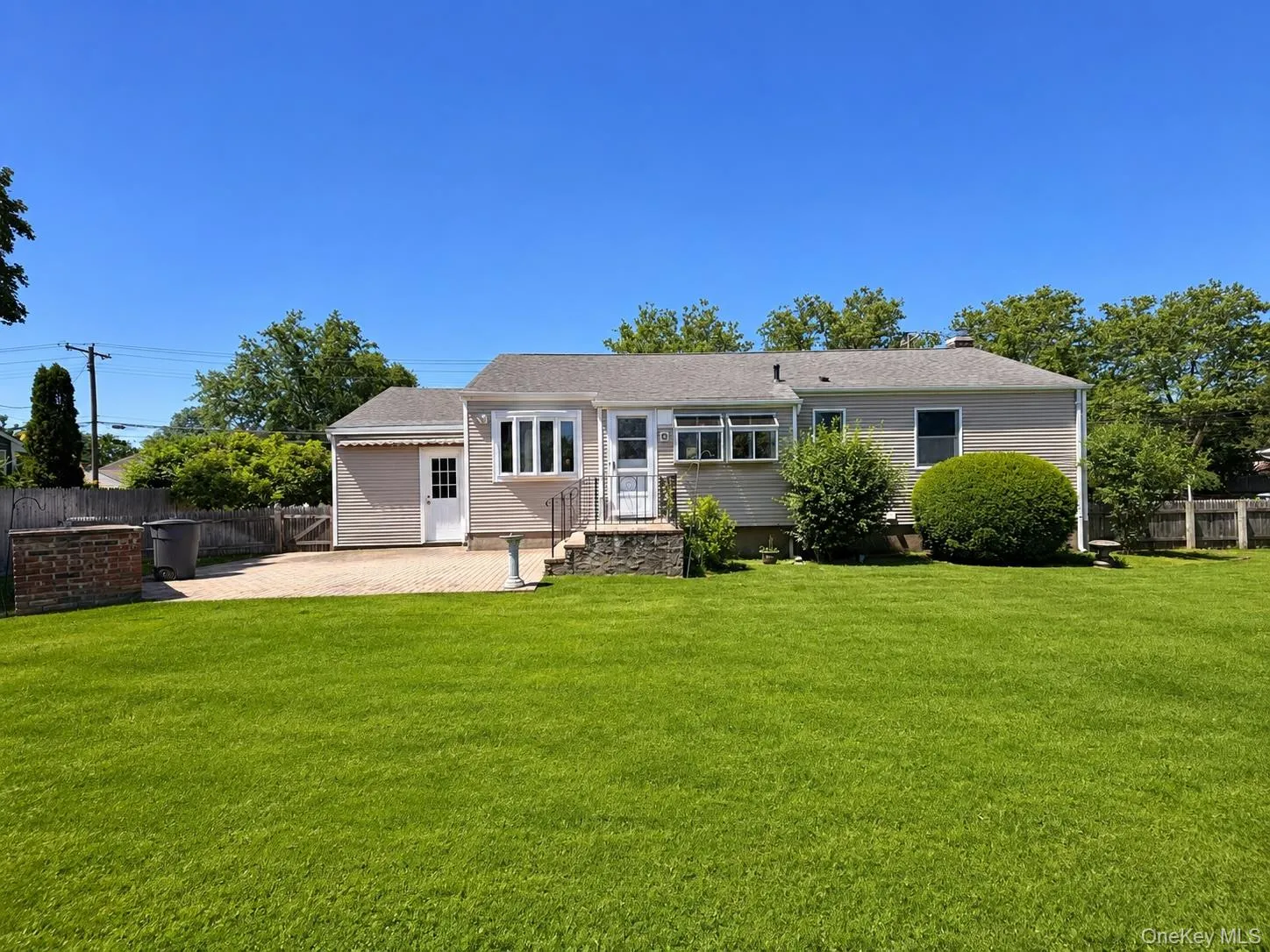Expansive green lawn with a single-story residence featuring light-colored siding Expansive green lawn with a single-story residence featuring light-colored siding