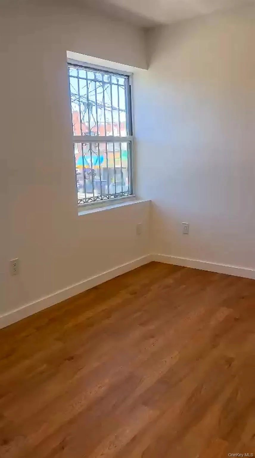 Well-lit room featuring wood-finish flooring, white baseboards, and neutral-toned walls Well-lit room featuring wood-finish flooring, white baseboards, and neutral-toned walls