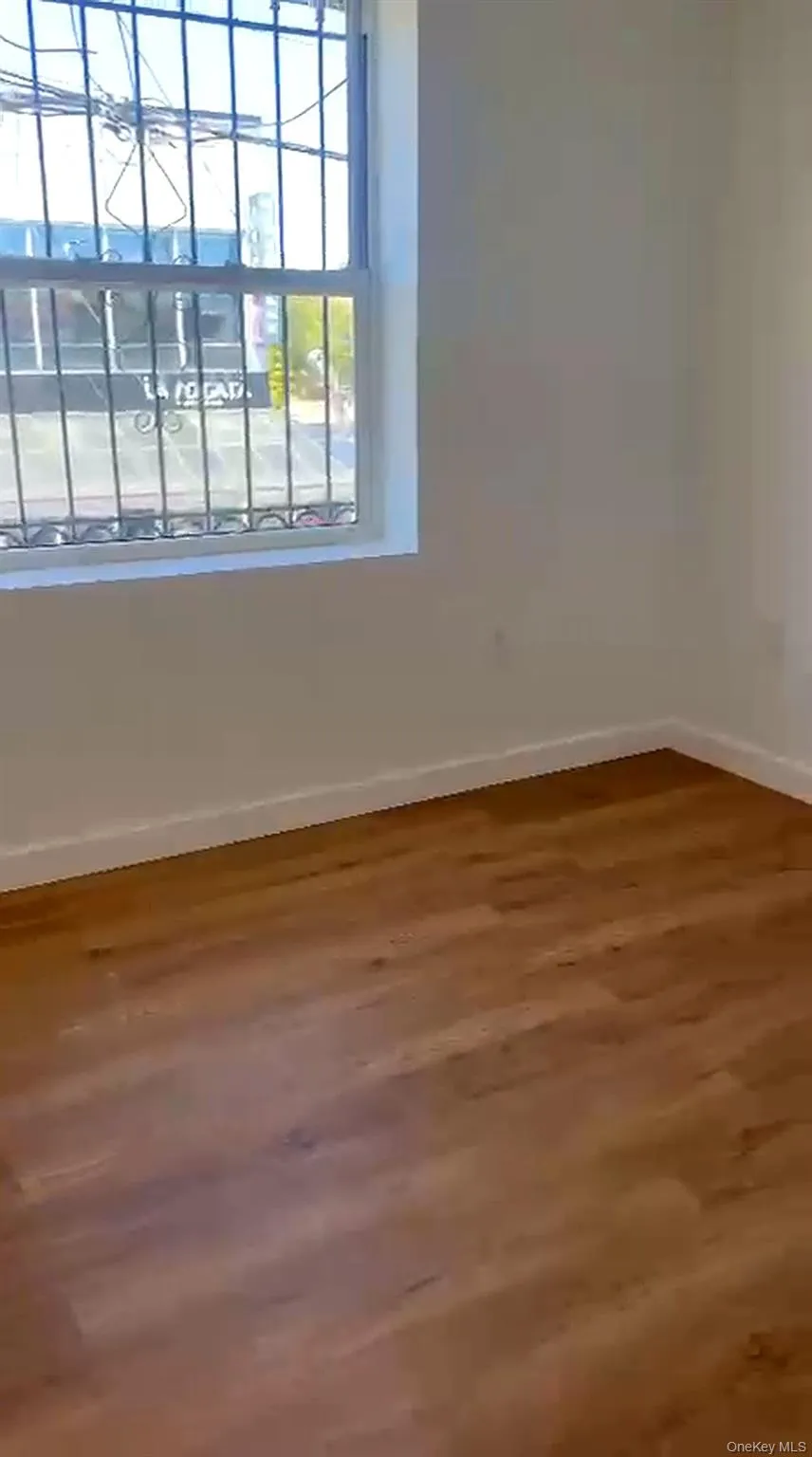 Interior room featuring wood-finish flooring, white baseboards, and light-toned walls Interior room featuring wood-finish flooring, white baseboards, and light-toned walls