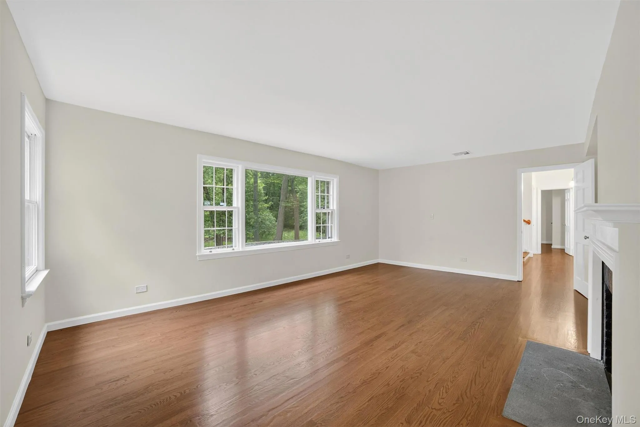 Unfurnished living room featuring wood finished floors and a fireplace with flush hearth Unfurnished living room featuring wood finished floors and a fireplace with flush hearth