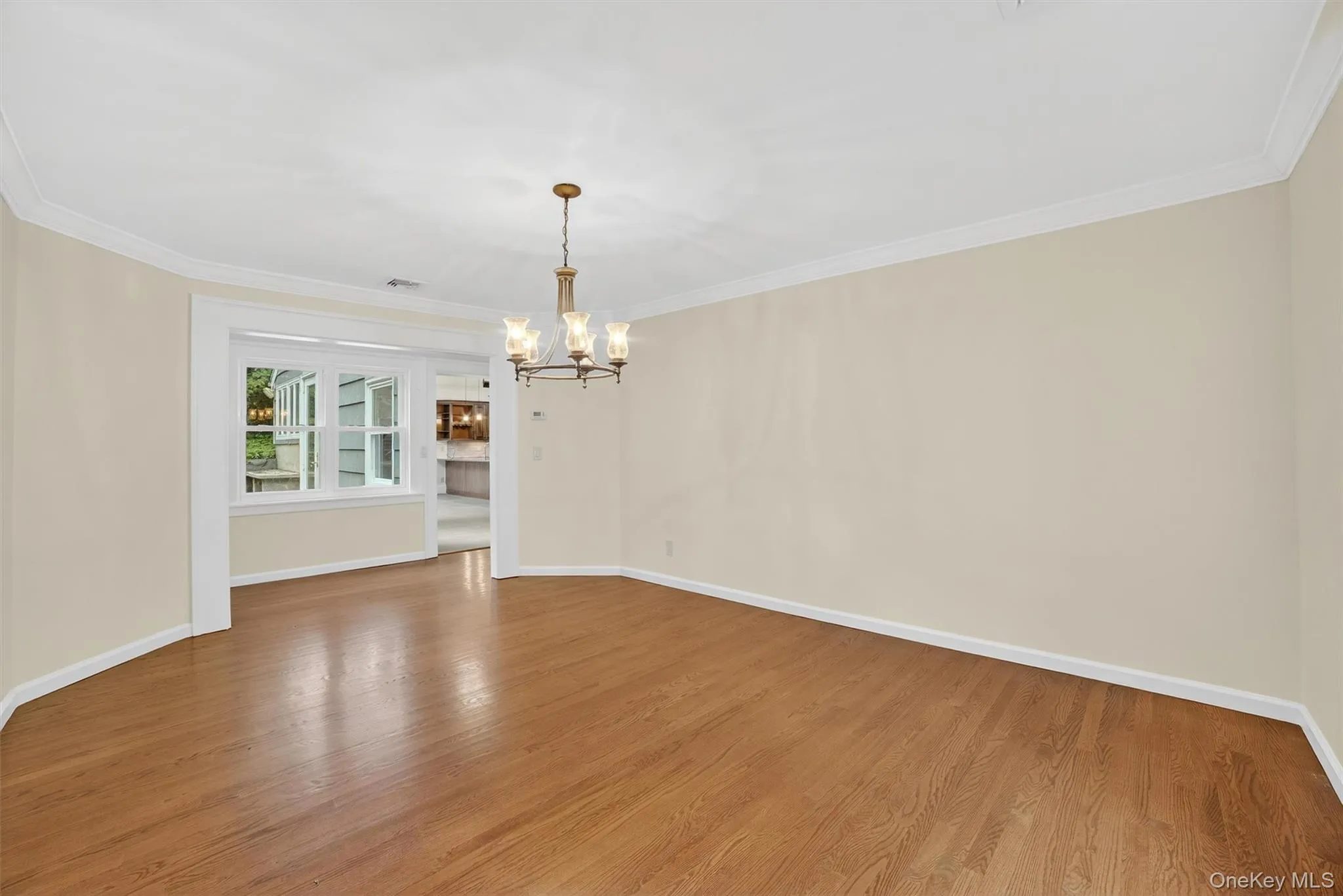 Spare room featuring a chandelier, wood finished floors, and ornamental molding Spare room featuring a chandelier, wood finished floors, and ornamental molding