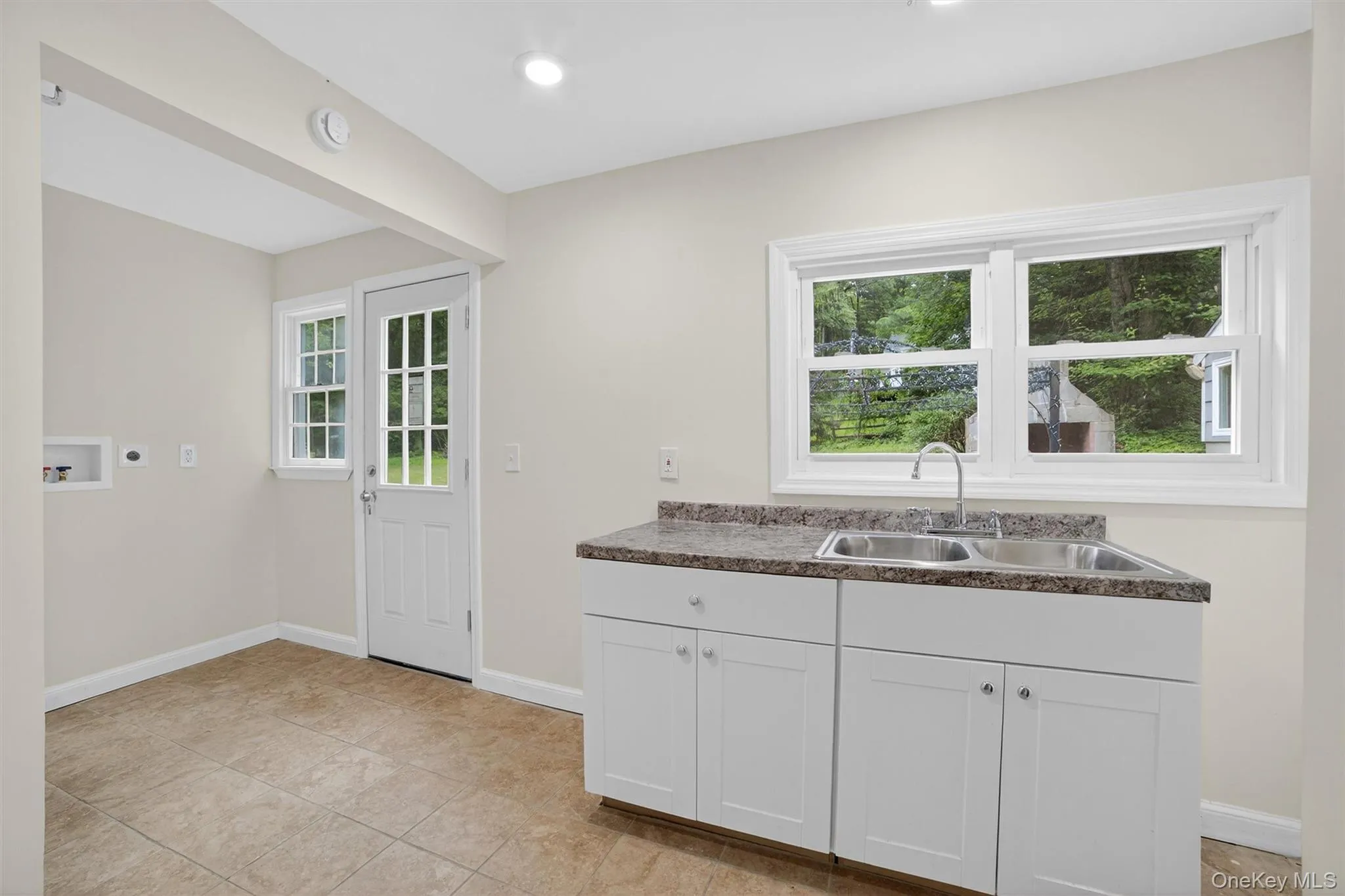 Kitchen featuring plenty of natural light, dark countertops, and white cabinetry Kitchen featuring plenty of natural light, dark countertops, and white cabinetry