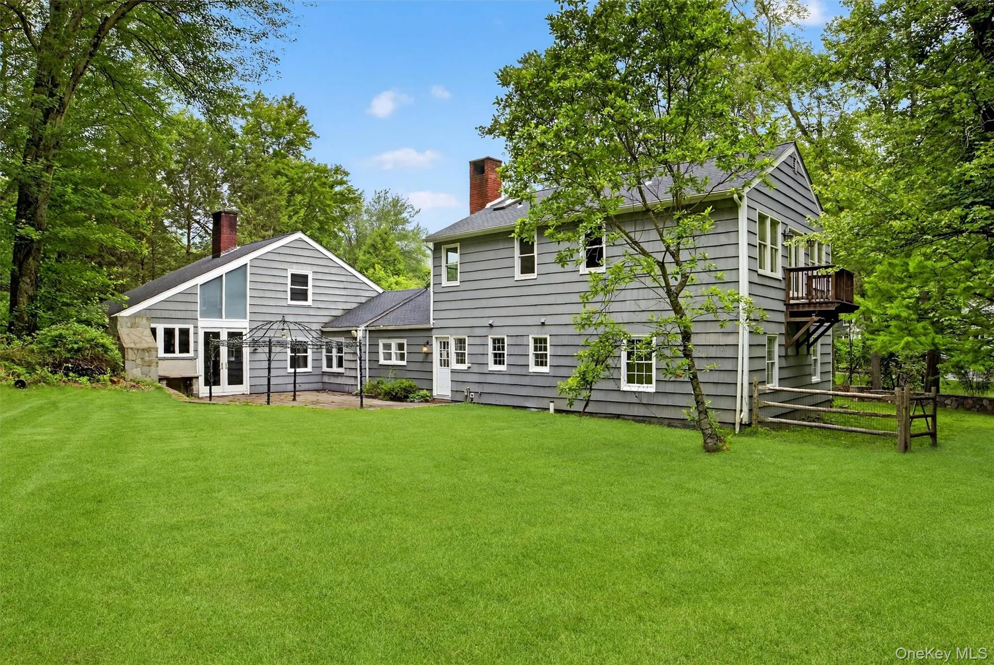 Back of house with a chimney, a yard, roof with shingles, and a wooden deck Back of house with a chimney, a yard, roof with shingles, and a wooden deck