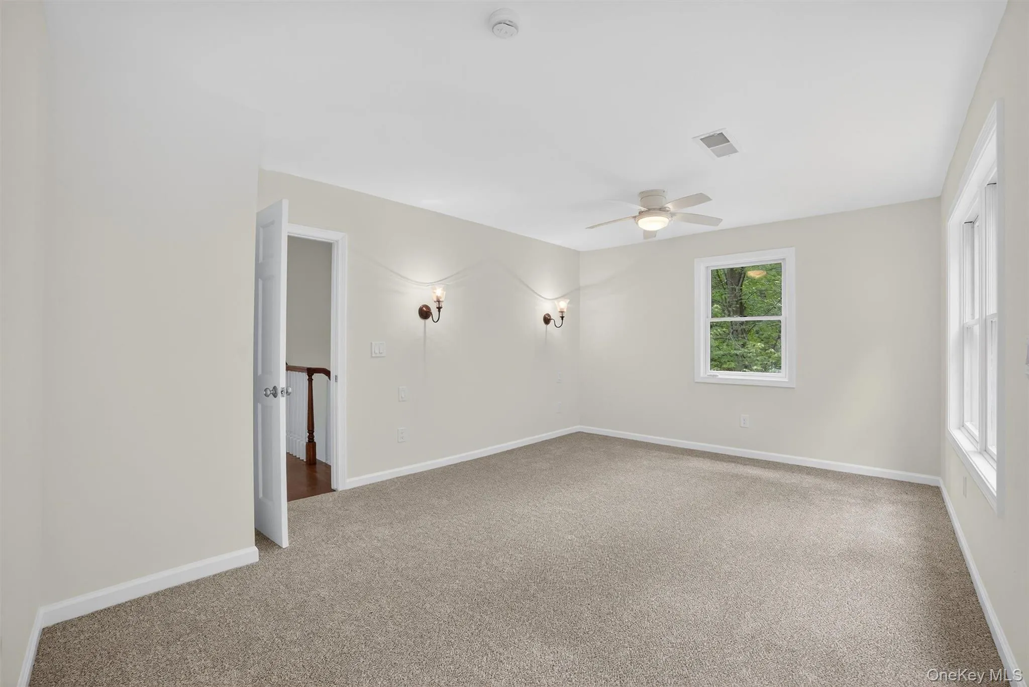 Carpeted empty room with a smoke detector and a ceiling fan Carpeted empty room with a smoke detector and a ceiling fan