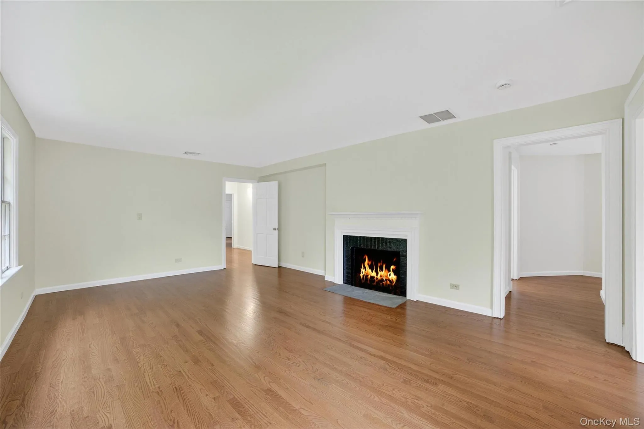 Unfurnished living room featuring a fireplace with flush hearth and light wood finished floors Unfurnished living room featuring a fireplace with flush hearth and light wood finished floors