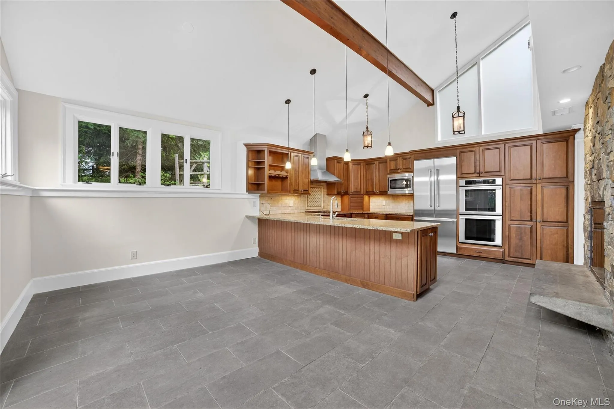 Kitchen with built in appliances, wall chimney range hood, brown cabinets, open shelves, and a peninsula Kitchen with built in appliances, wall chimney range hood, brown cabinets, open shelves, and a peninsula
