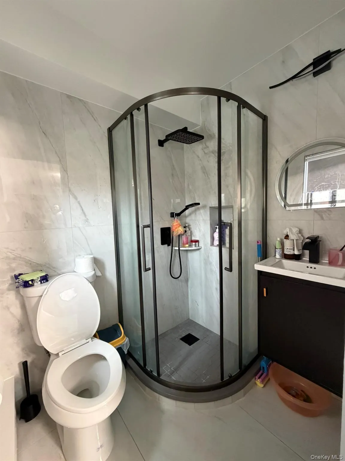 Bathroom featuring tile walls, vanity, a marble finish shower, and tile patterned floors Bathroom featuring tile walls, vanity, a marble finish shower, and tile patterned floors