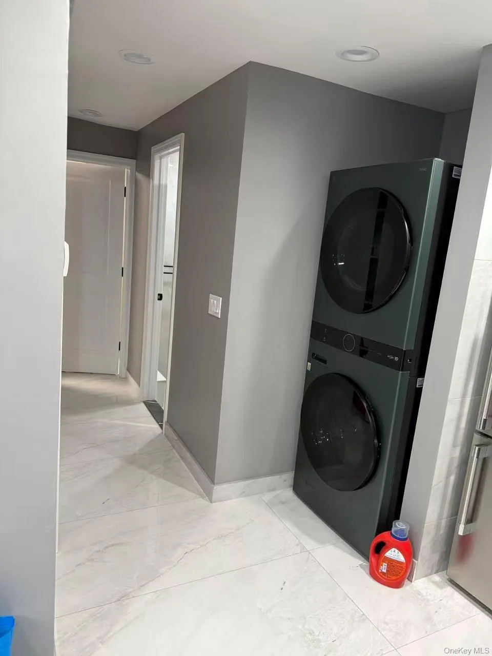 Washroom with stacked washer / drying machine and baseboards Washroom with stacked washer / drying machine and baseboards