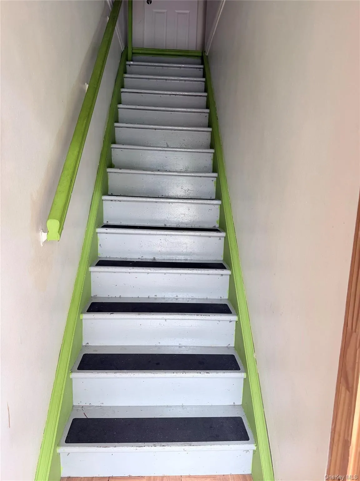 Staircase featuring white treads with black non-slip strips and bright green stringers and handrail, leading to the 2nd. floor Staircase featuring white treads with black non-slip strips and bright green stringers and handrail, leading to the 2nd. floor