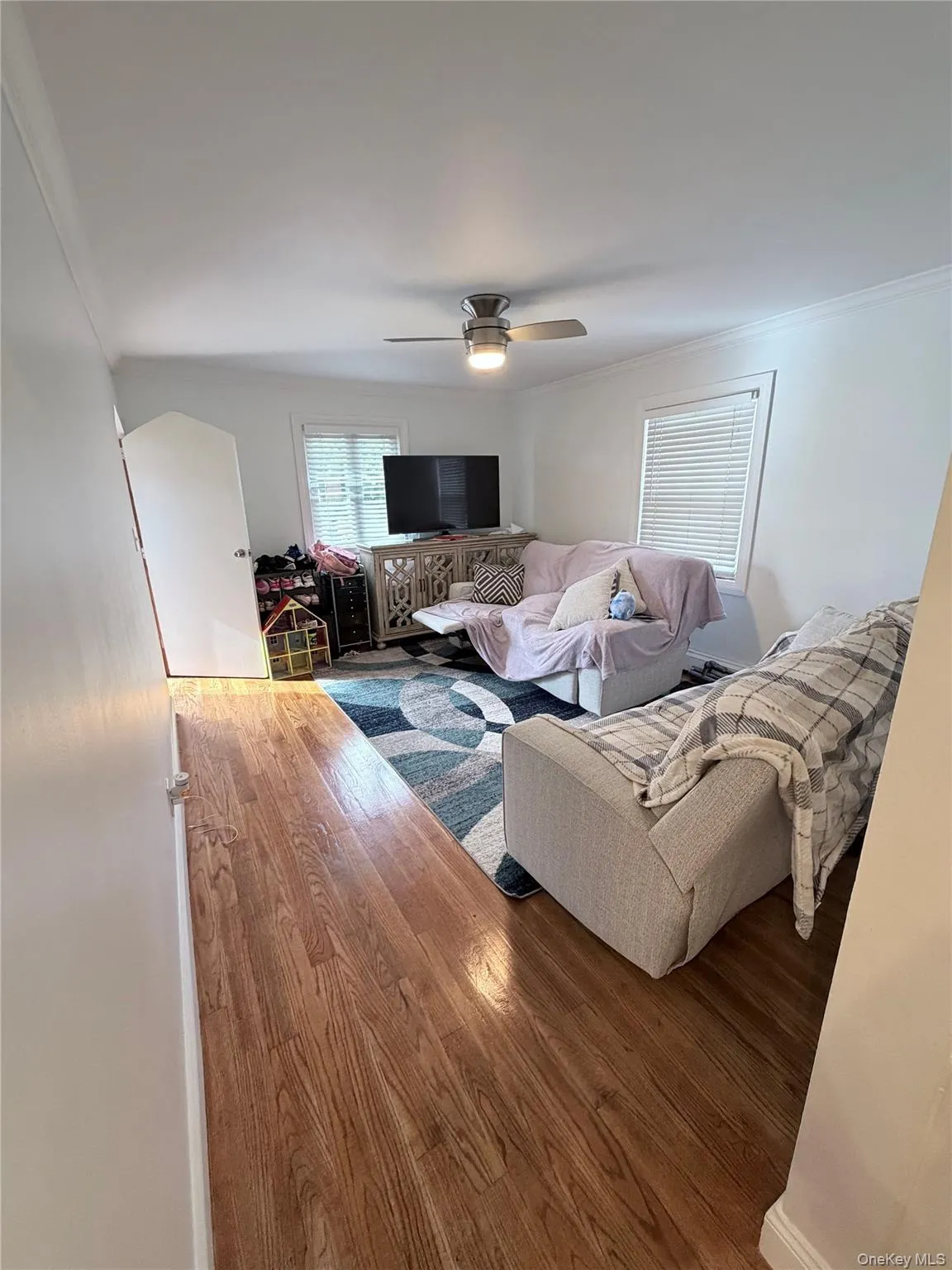 Hardwood-style flooring extends through this room, featuring white walls and crown molding Hardwood-style flooring extends through this room, featuring white walls and crown molding