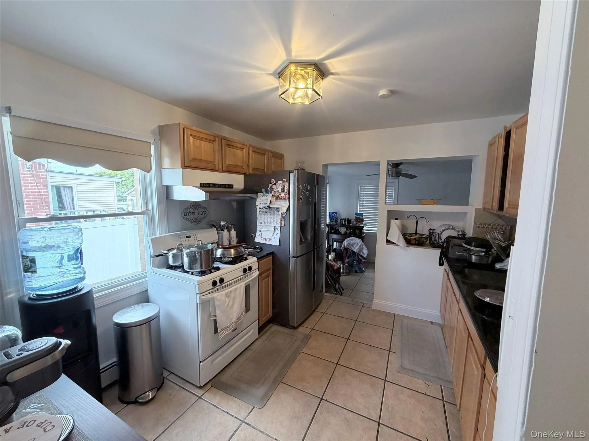 Kitchen featuring wood cabinetry, a white gas range, and a stainless steel refrigerator Kitchen featuring wood cabinetry, a white gas range, and a stainless steel refrigerator