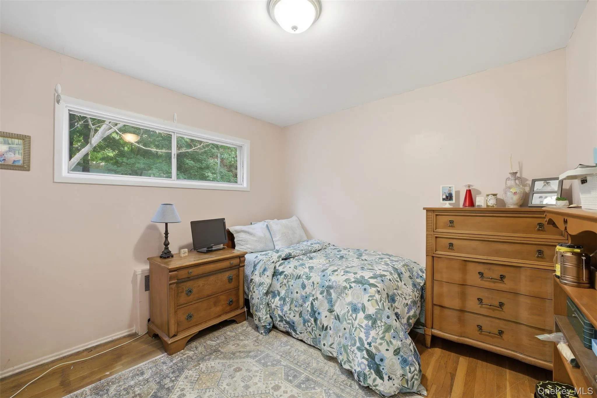 2nd Bedroom featuring a horizontal window, wood-finish flooring, a flush-mount ceiling light, and light-toned wall paint 2nd Bedroom featuring a horizontal window, wood-finish flooring, a flush-mount ceiling light, and light-toned wall paint