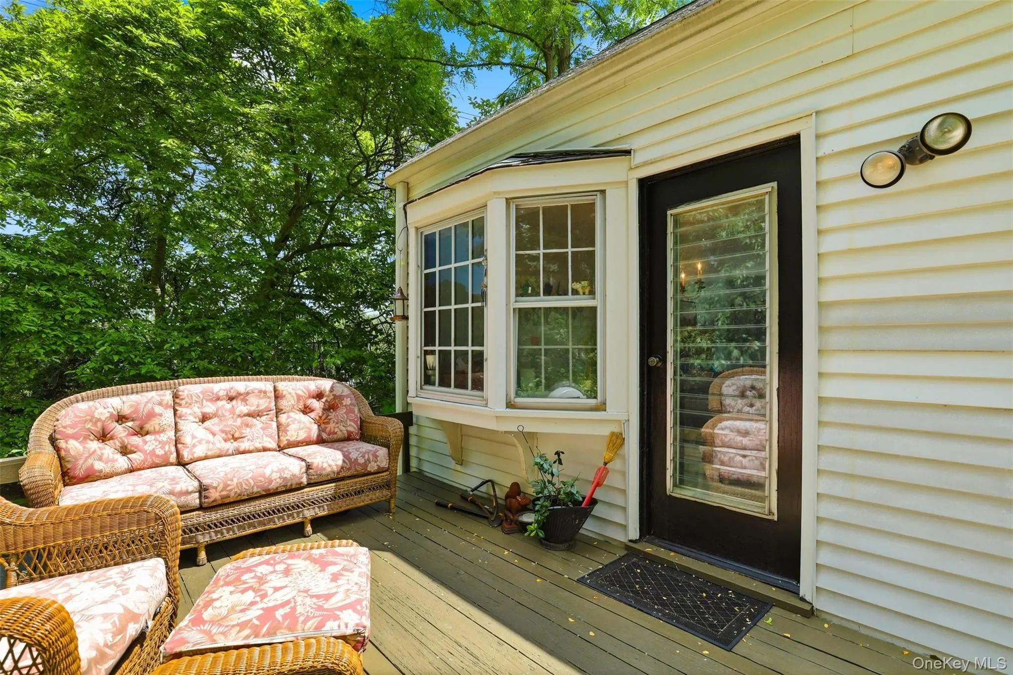 Outdoor deck space featuring a bay window, a full-lite exterior door, and white siding Outdoor deck space featuring a bay window, a full-lite exterior door, and white siding