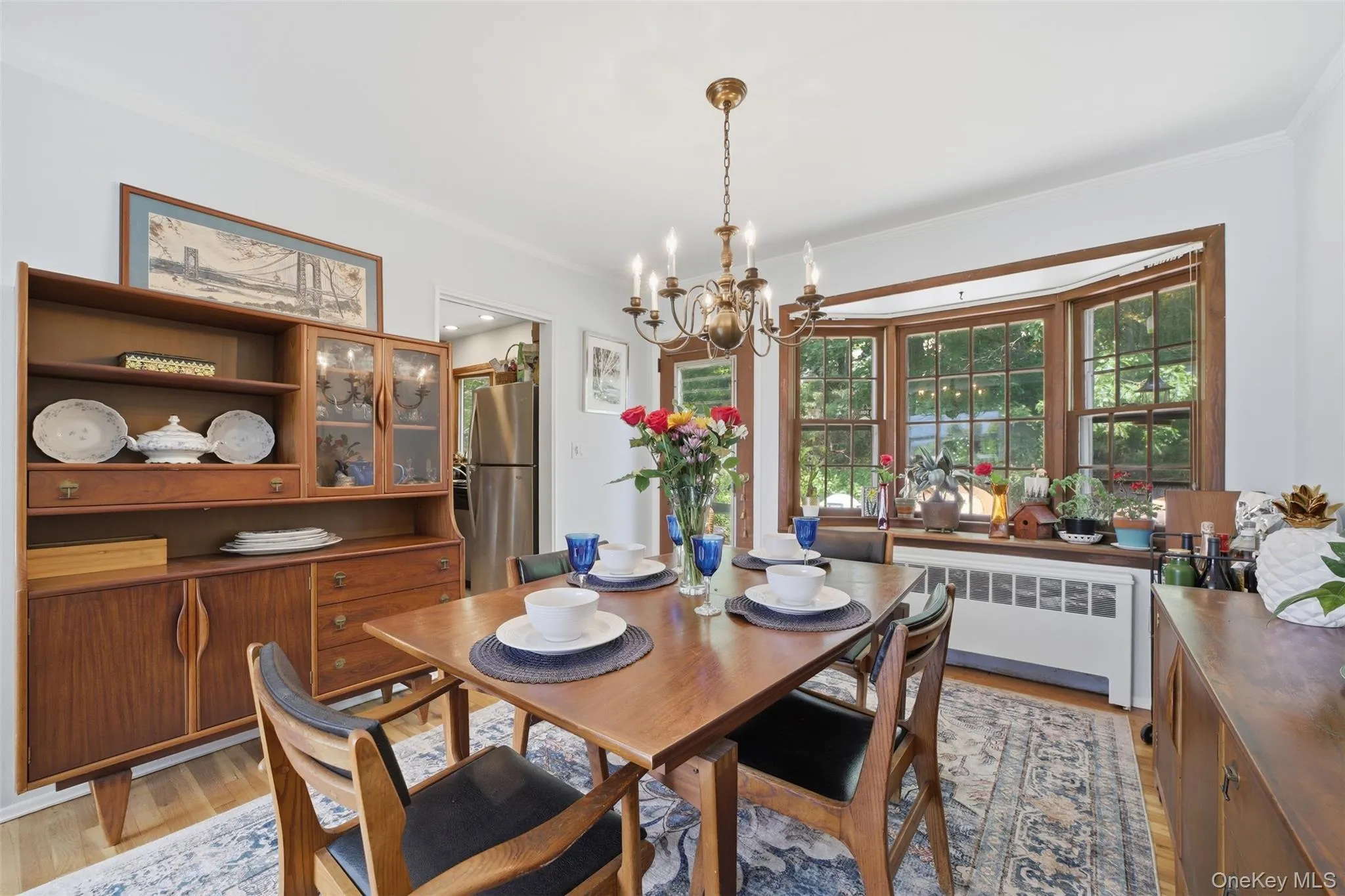 Bay window with wood trim, chandelier lighting, hardwood-finish flooring, and crown molding Bay window with wood trim, chandelier lighting, hardwood-finish flooring, and crown molding