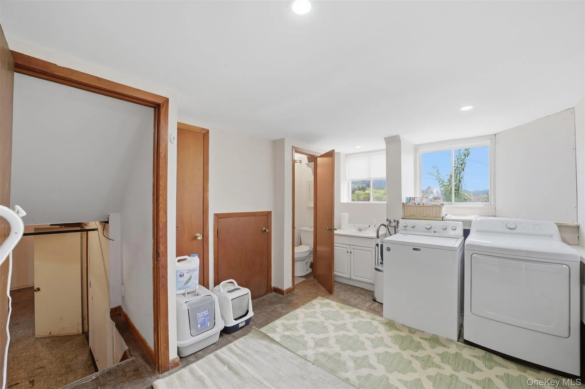 Dedicated laundry area featuring a utility sink, white cabinetry, and large window and powder room Dedicated laundry area featuring a utility sink, white cabinetry, and large window and powder room