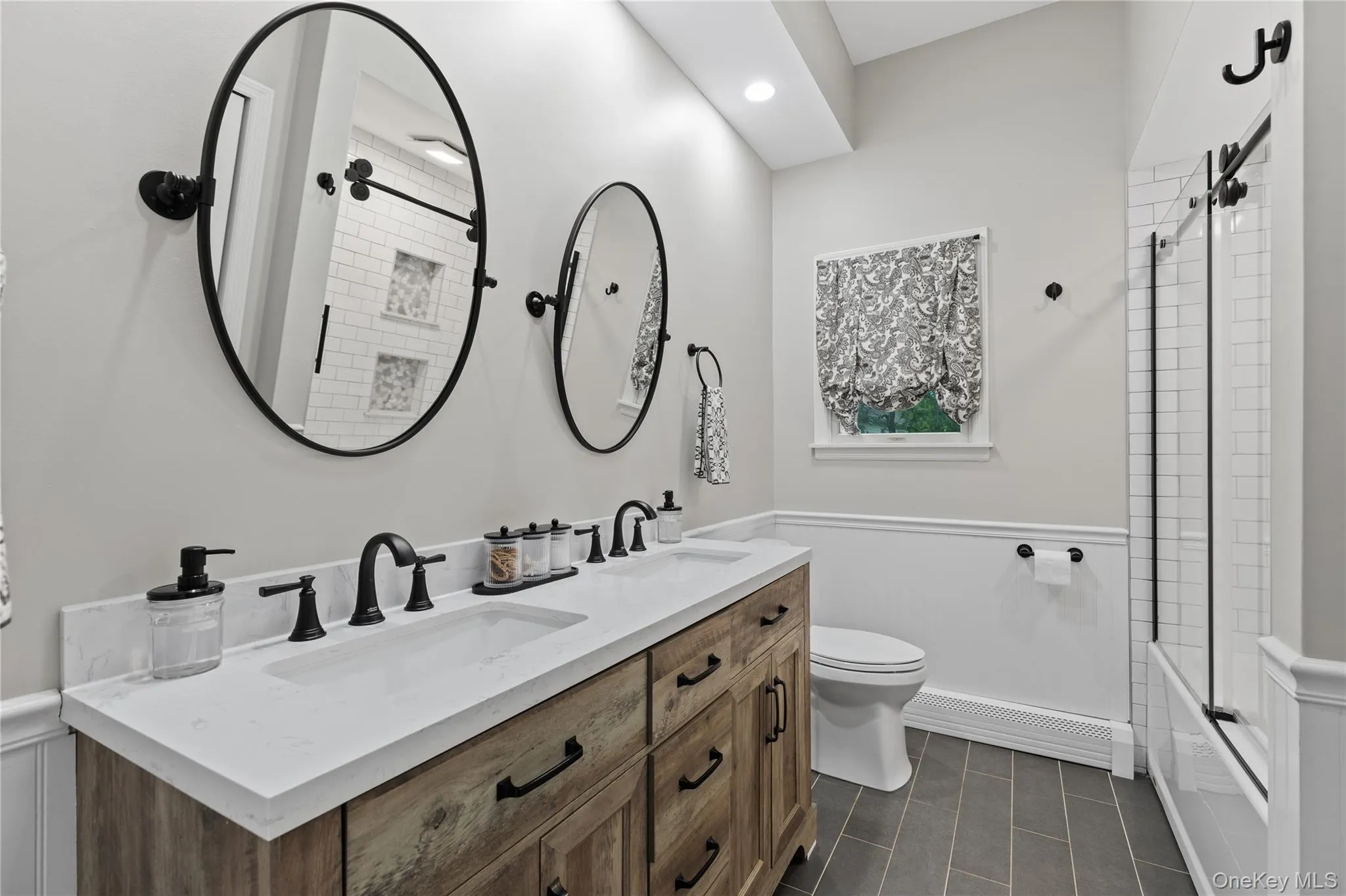 Double vanity with wood-finish cabinetry, white countertop, and dual sinks Double vanity with wood-finish cabinetry, white countertop, and dual sinks