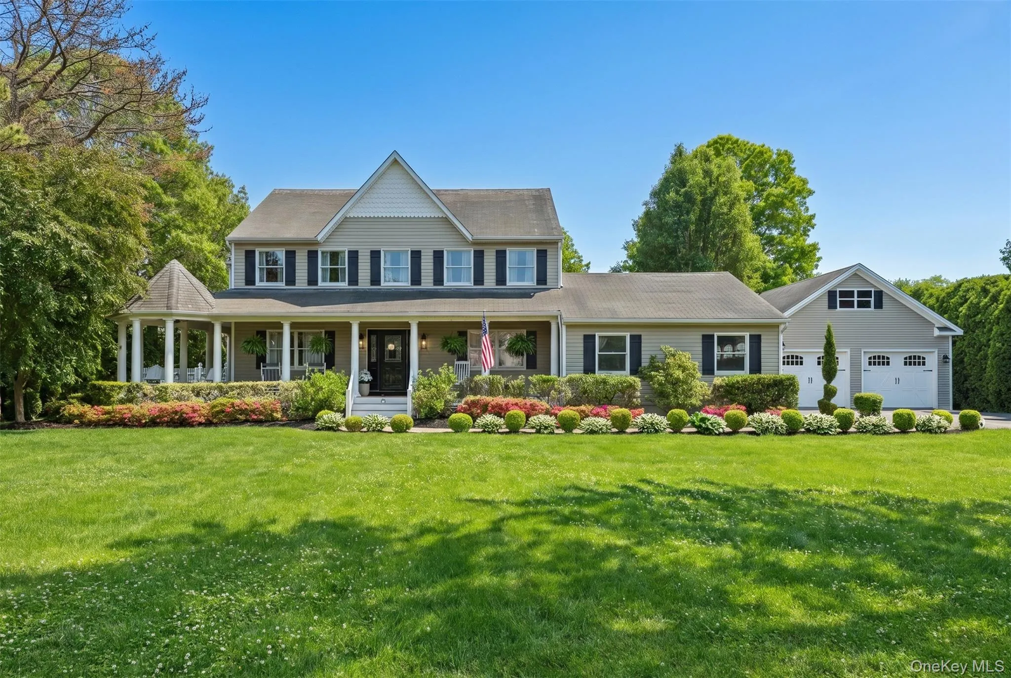 Two-story residence featuring light-colored siding and a covered front porch with white columns Two-story residence featuring light-colored siding and a covered front porch with white columns