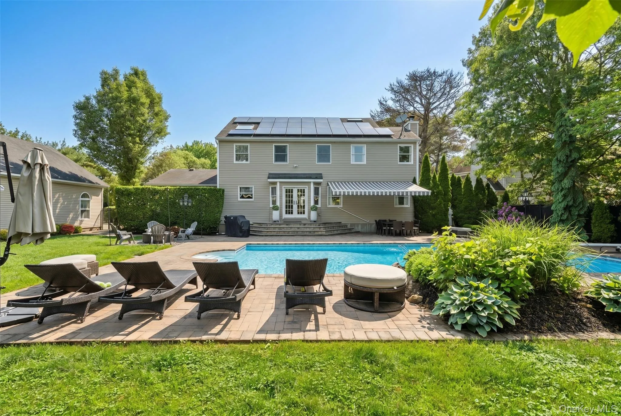 Expansive backyard featuring a rectangular in-ground pool, paver patio, mature landscaping, and privacy hedging Expansive backyard featuring a rectangular in-ground pool, paver patio, mature landscaping, and privacy hedging