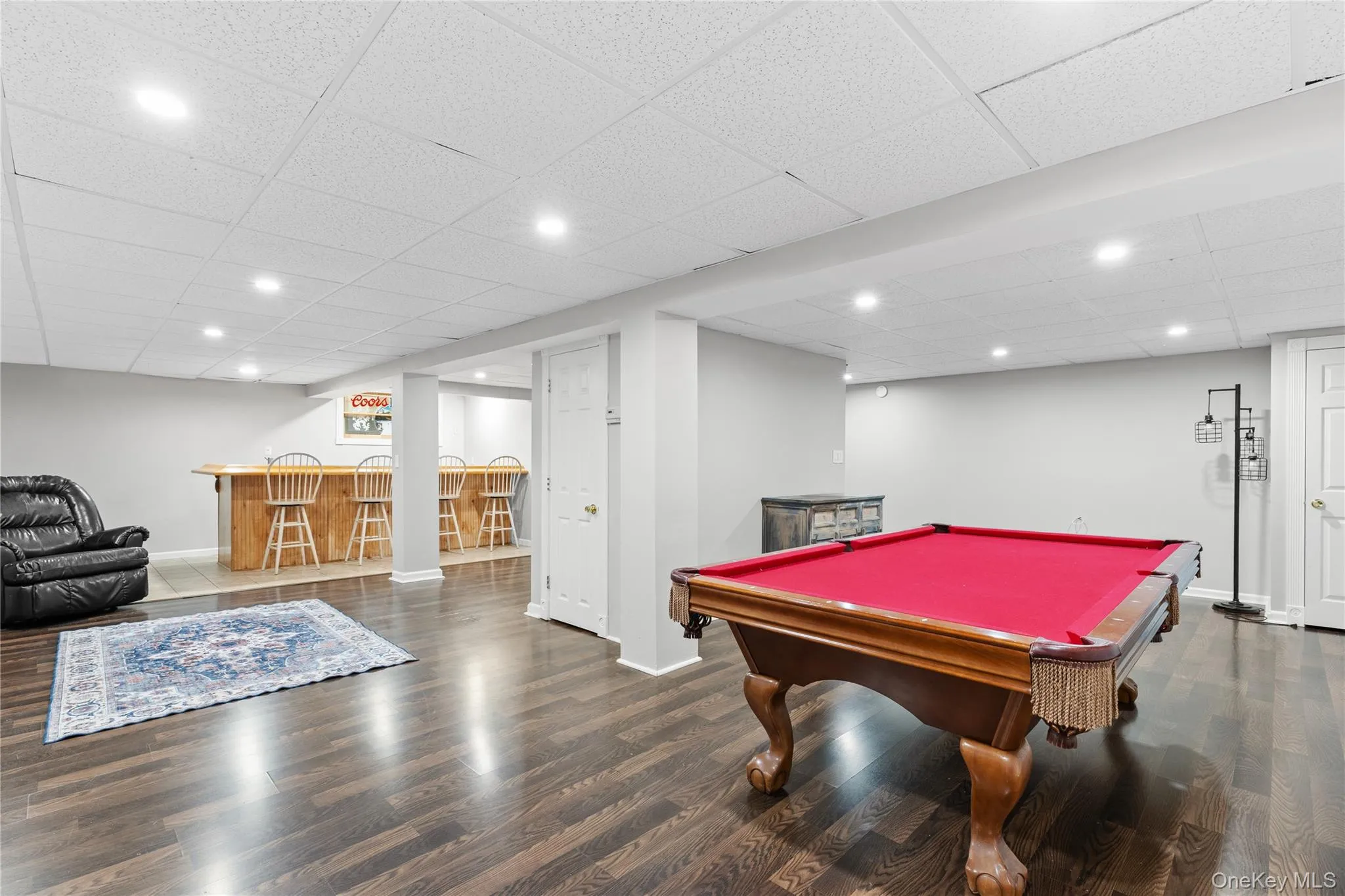 Spacious entertainment area featuring, recessed lighting, a built-in bar with wood paneling, and a white paneled door Spacious entertainment area featuring, recessed lighting, a built-in bar with wood paneling, and a white paneled door