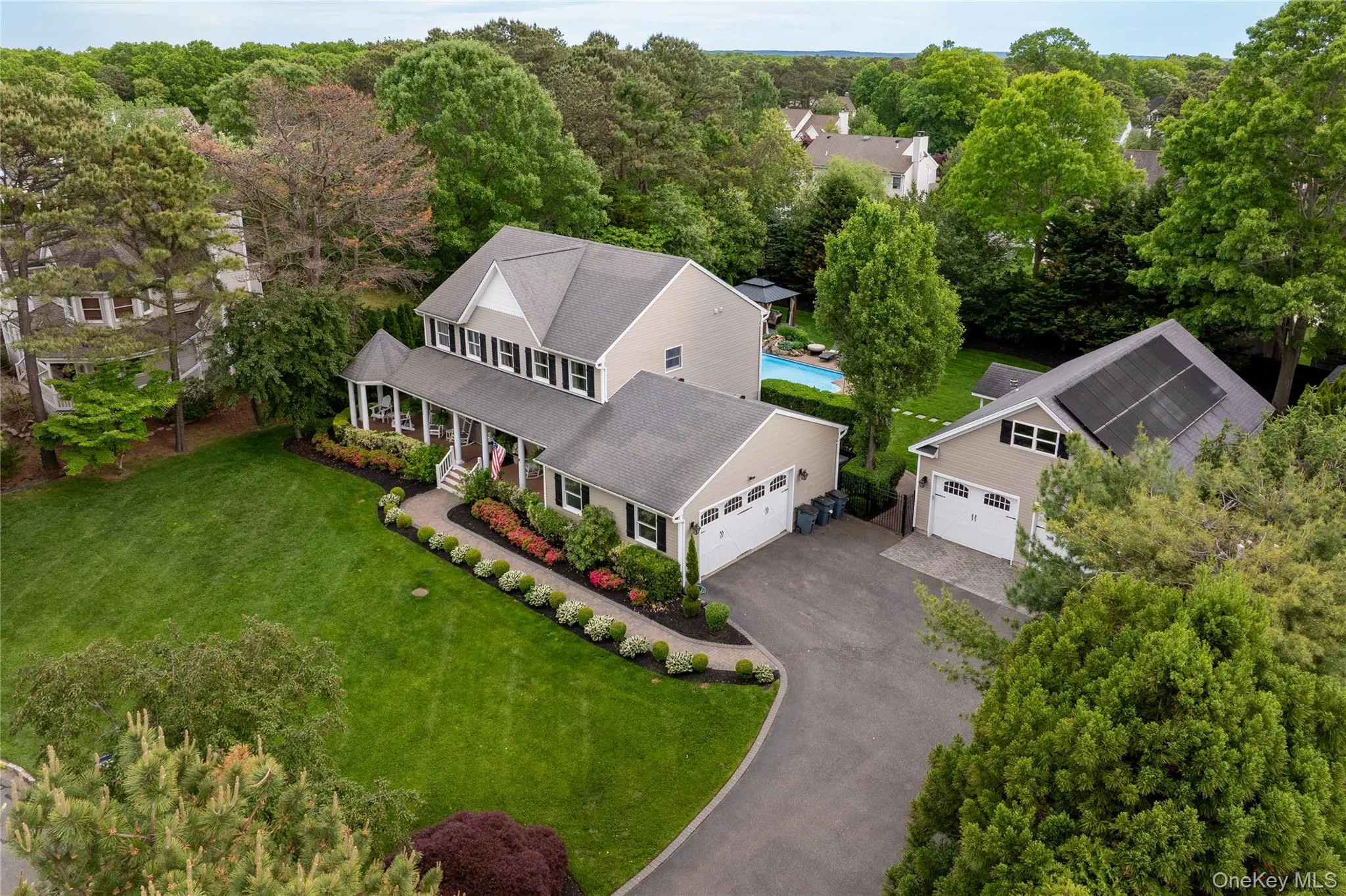 Expansive property featuring a two-story residence with covered porch, detached garage with solar panels, swimming pool, and mature landscaping Expansive property featuring a two-story residence with covered porch, detached garage with solar panels, swimming pool, and mature landscaping