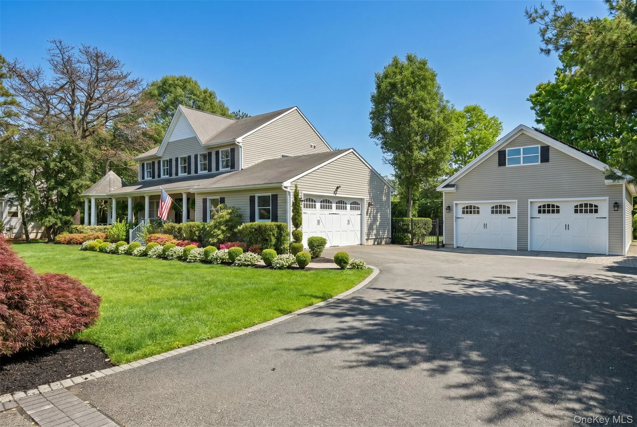 Expansive property featuring a multi-car driveway, a detached two-car garage with overhead windows, and a separate attached two-car garage Expansive property featuring a multi-car driveway, a detached two-car garage with overhead windows, and a separate attached two-car garage