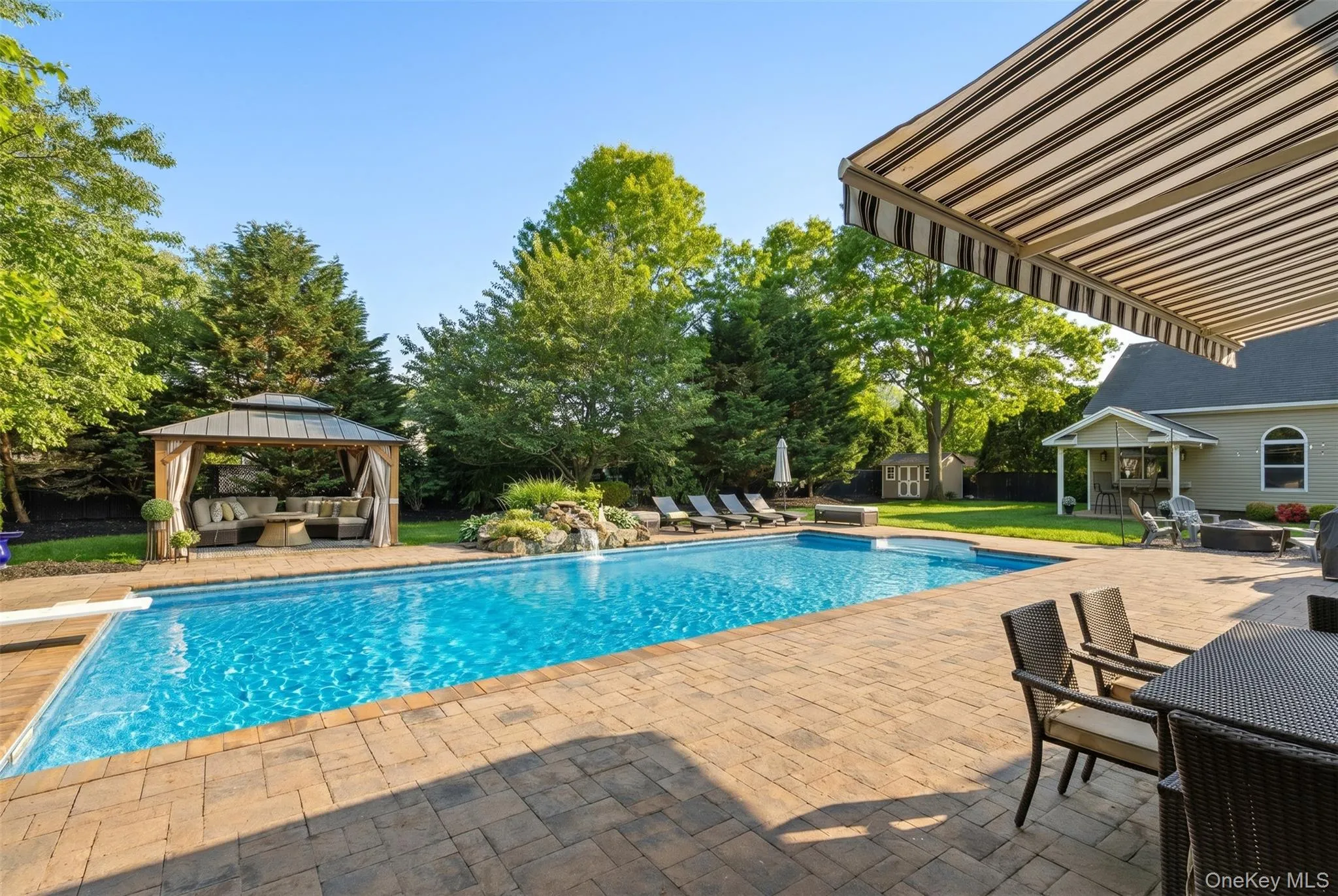 Expansive paver patio surrounding a rectangular swimming pool with a diving board Expansive paver patio surrounding a rectangular swimming pool with a diving board