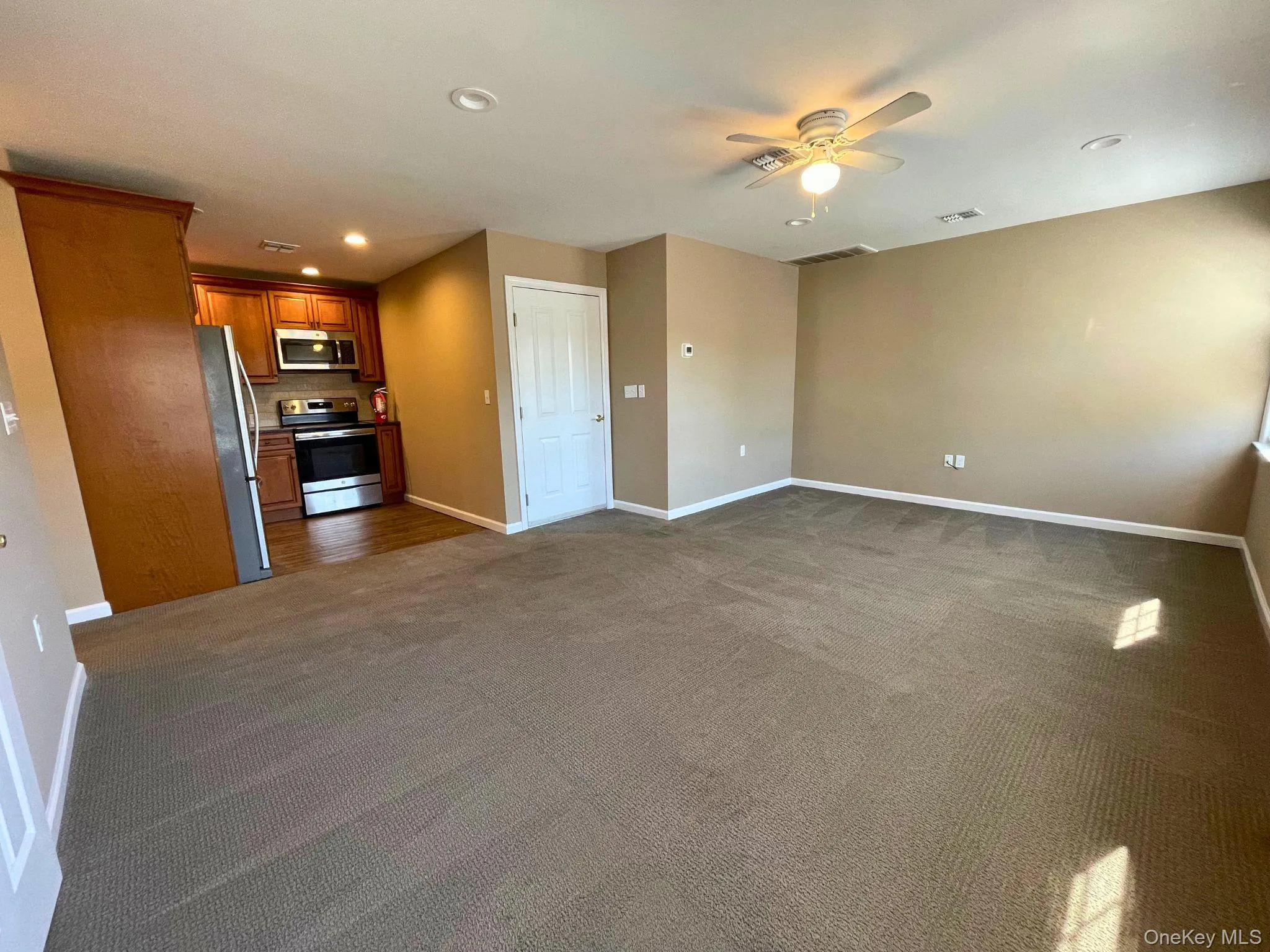 Open-concept living space featuring neutral carpeted flooring and recessed lighting Open-concept living space featuring neutral carpeted flooring and recessed lighting