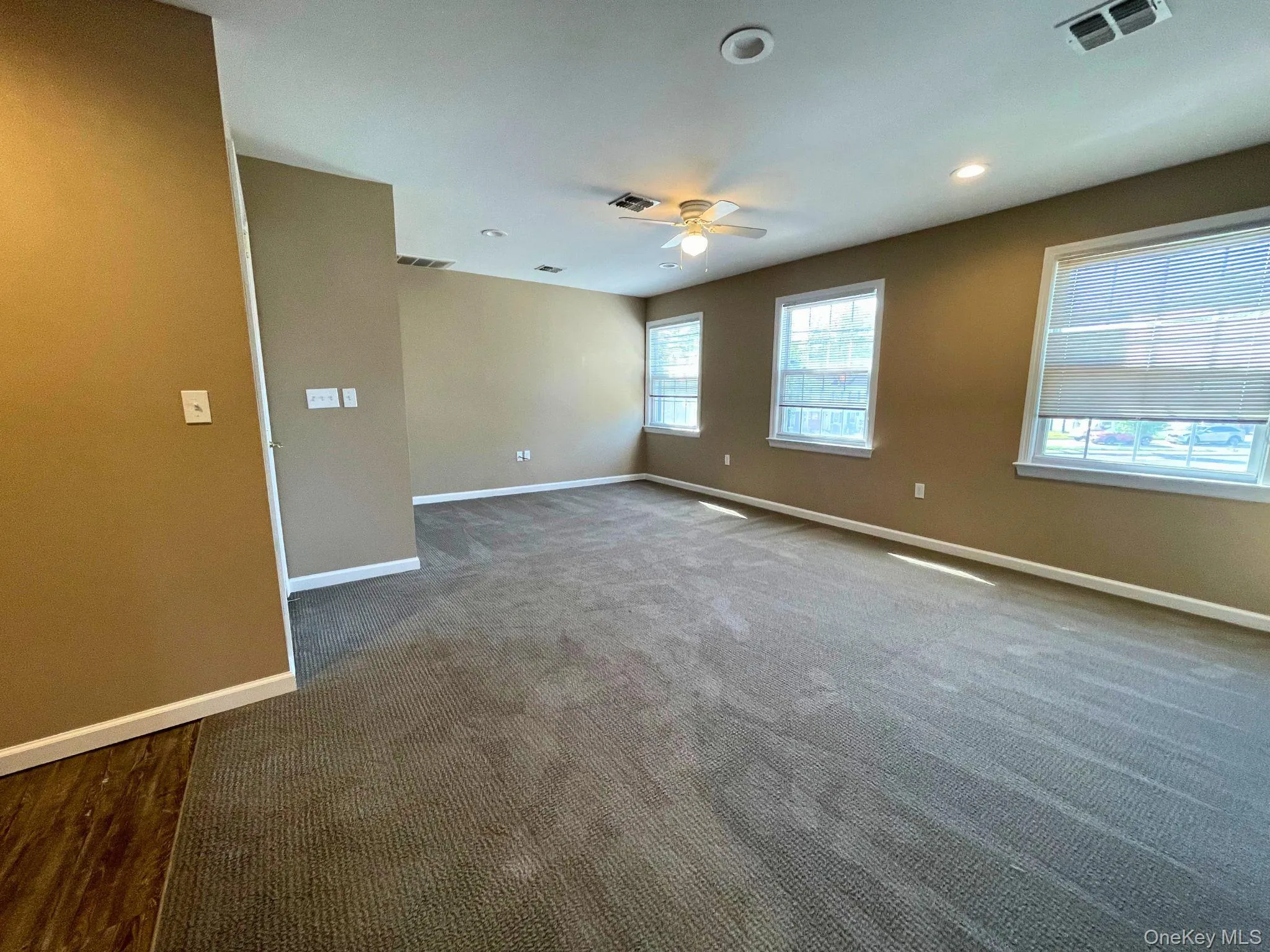Spacious room featuring neutral-toned walls and plush gray carpeting Spacious room featuring neutral-toned walls and plush gray carpeting