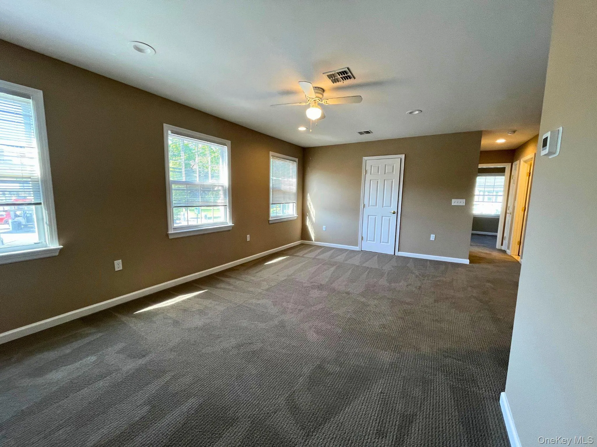 Spacious room featuring neutral carpeting and multiple windows Spacious room featuring neutral carpeting and multiple windows