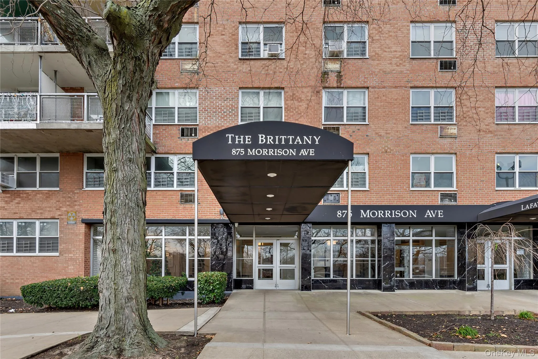 Brick multi-story building featuring a prominent covered entrance with "THE BRITTANY" and street address signage Brick multi-story building featuring a prominent covered entrance with "THE BRITTANY" and street address signage