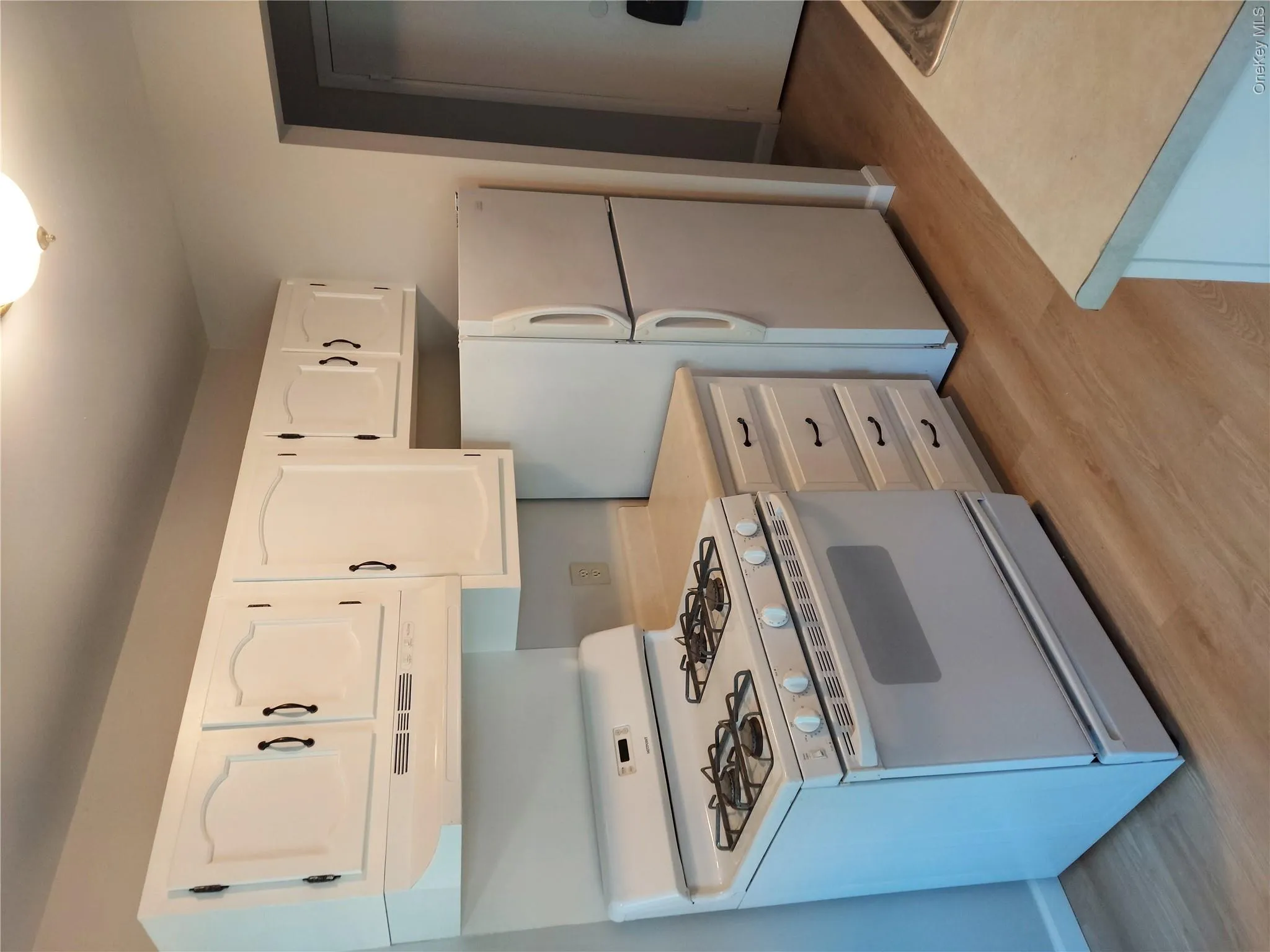 Kitchen featuring white cabinetry, a gas range, white refrigerator, light-toned countertops, and wood-finish flooring Kitchen featuring white cabinetry, a gas range, white refrigerator, light-toned countertops, and wood-finish flooring