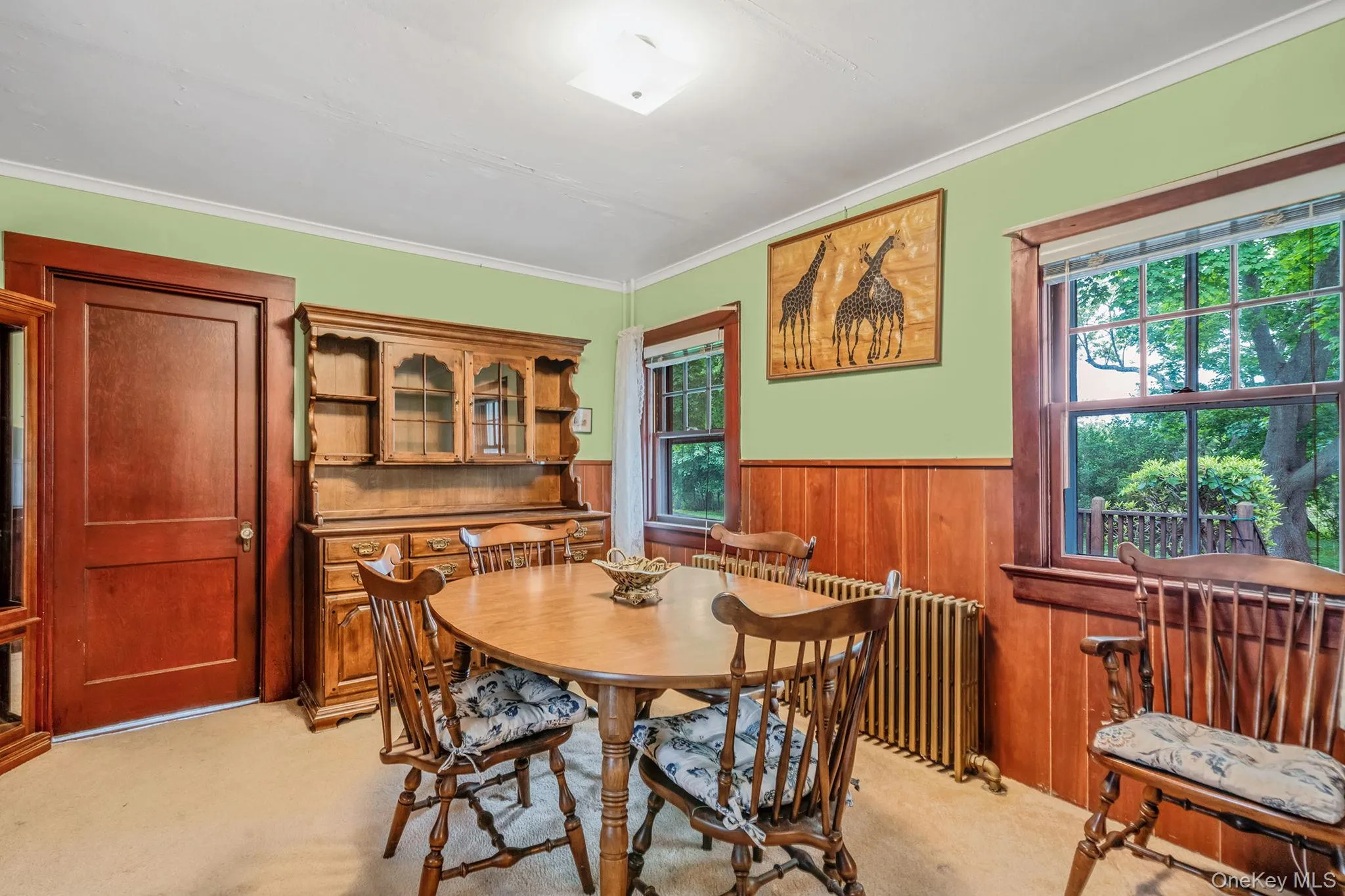 Dining room featuring wood paneling, two windows with exterior views, and a warm wood-finish door to 2nd floor. Dining room featuring wood paneling, two windows with exterior views, and a warm wood-finish door to 2nd floor.