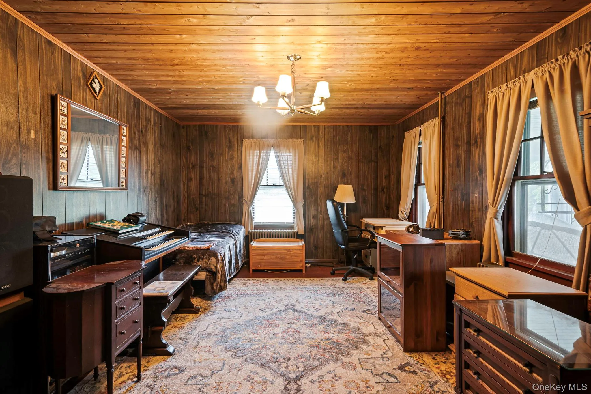 Wood-paneled room featuring a wood-finish plank ceiling, multiple windows and a chandelier Wood-paneled room featuring a wood-finish plank ceiling, multiple windows and a chandelier