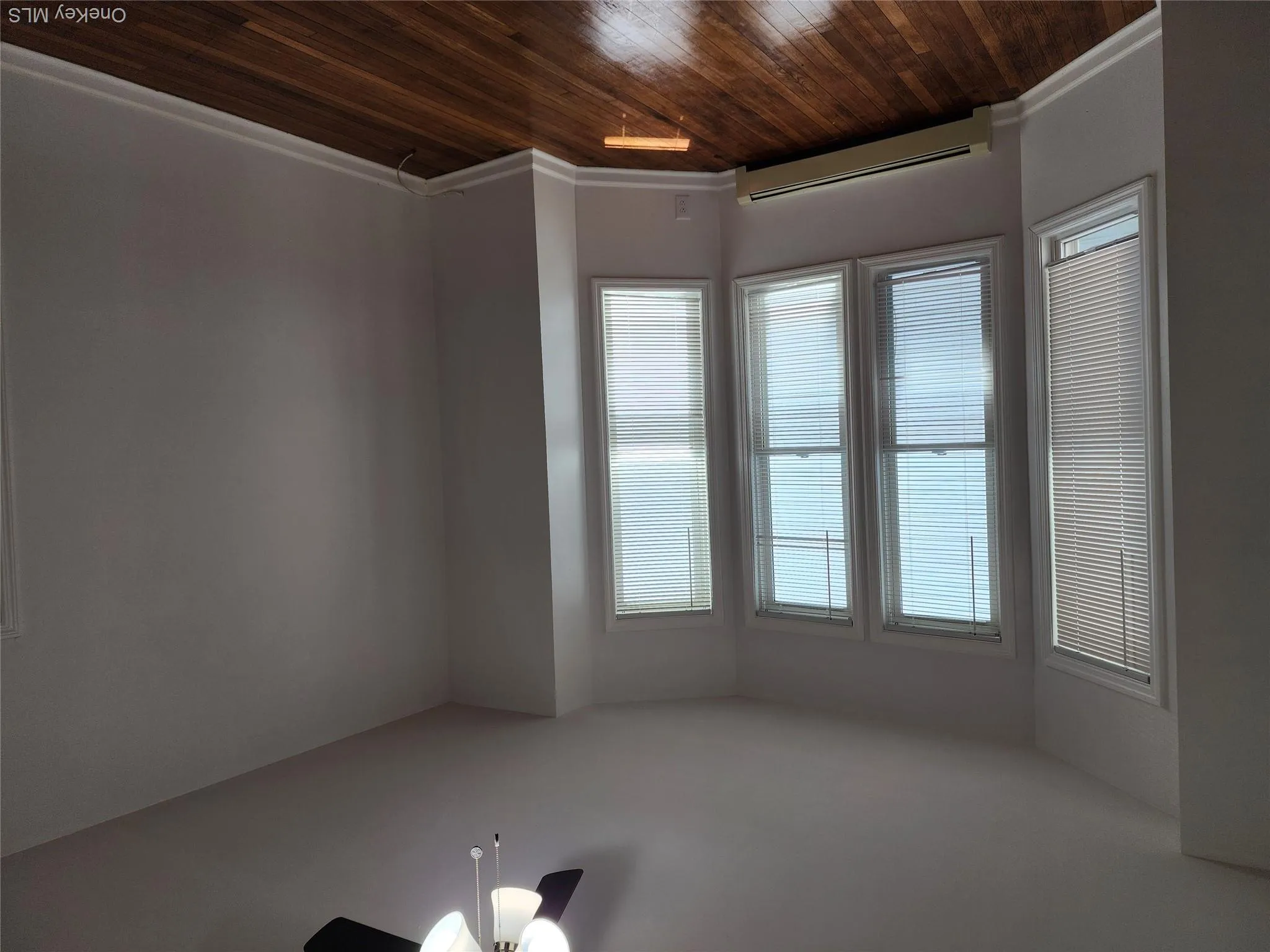 Bay window with multiple vertical blinds, wood-finish flooring, white baseboards, and a ceiling fan with integrated lighting Bay window with multiple vertical blinds, wood-finish flooring, white baseboards, and a ceiling fan with integrated lighting