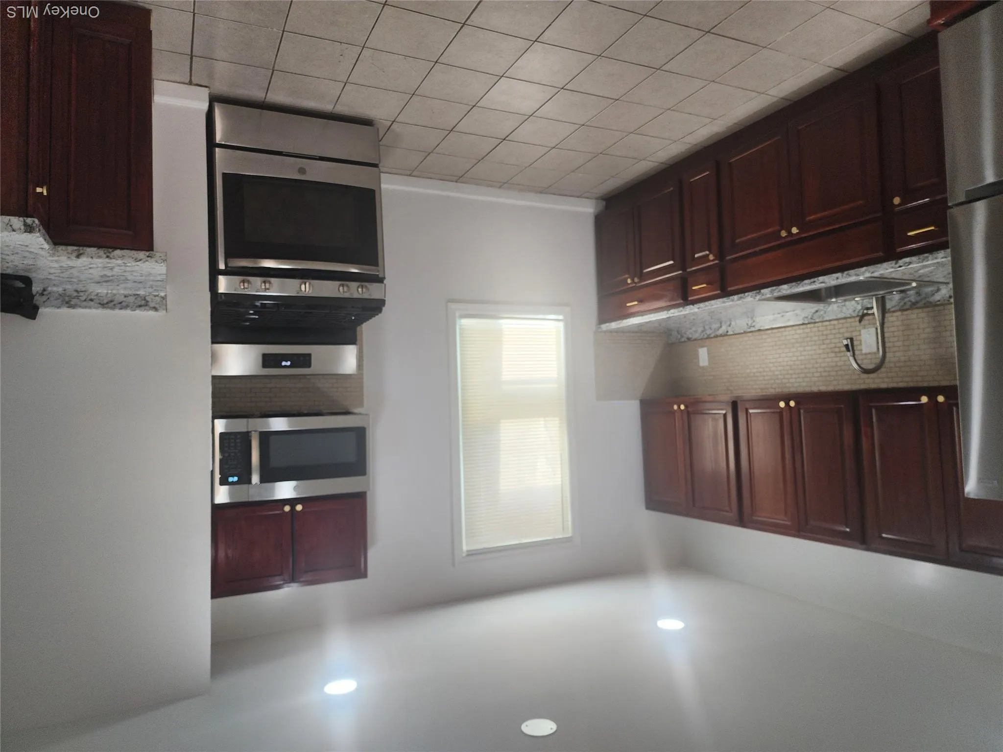 Kitchen featuring dark wood cabinetry, light-toned tiled flooring, granite-look countertops, and a full suite of stainless steel appliances Kitchen featuring dark wood cabinetry, light-toned tiled flooring, granite-look countertops, and a full suite of stainless steel appliances