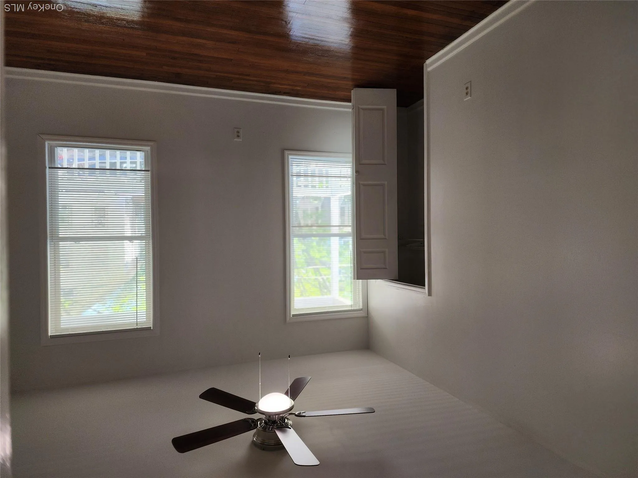 Large Primary bedroom featuring rich wood-finish flooring, two double-hung windows with blinds, a ceiling fan with integrated lighting, a built-in closet with a paneled door, and neutral-toned walls Large Primary bedroom featuring rich wood-finish flooring, two double-hung windows with blinds, a ceiling fan with integrated lighting, a built-in closet with a paneled door, and neutral-toned walls