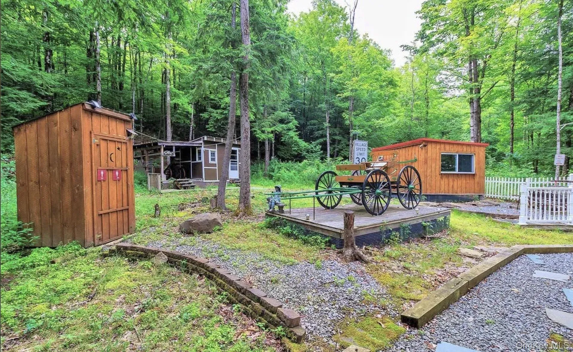 Wood-paneled outbuilding and separate shed set within a natural, wooded environment Wood-paneled outbuilding and separate shed set within a natural, wooded environment