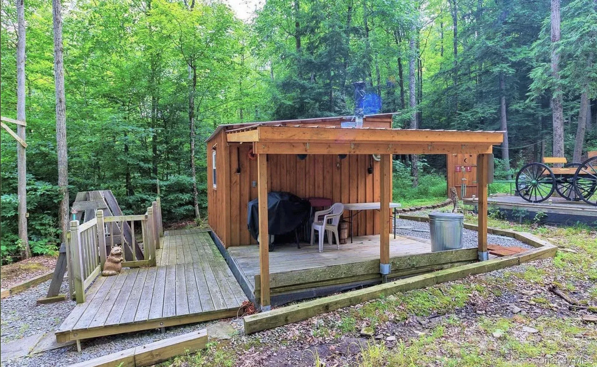 Wood-sided outbuilding with an attached covered porch and a separate wooden deck Wood-sided outbuilding with an attached covered porch and a separate wooden deck