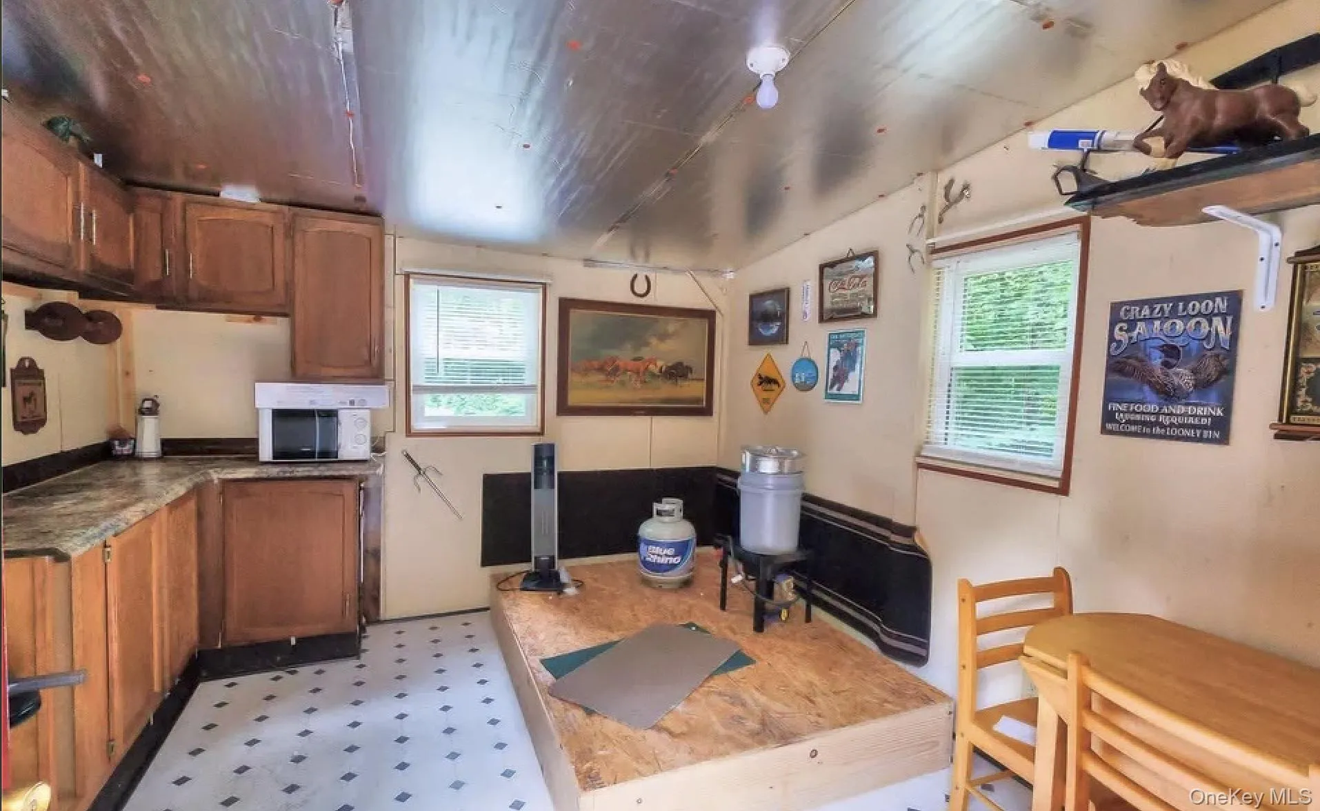 Compact kitchen area featuring wood-finish cabinetry, a microwave oven, and laminate countertops Compact kitchen area featuring wood-finish cabinetry, a microwave oven, and laminate countertops