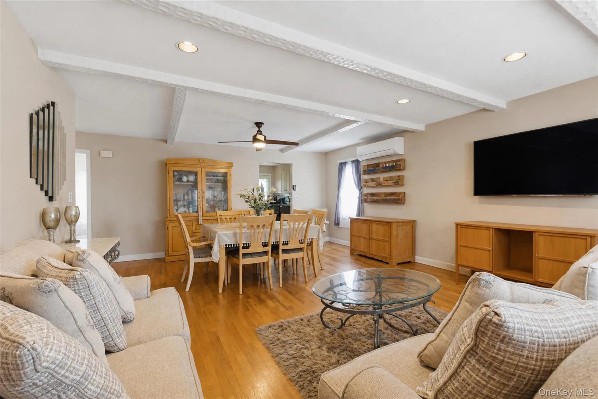 Open-concept living and dining area featuring wood-finish flooring, white coffered ceilings, and recessed lighting Open-concept living and dining area featuring wood-finish flooring, white coffered ceilings, and recessed lighting