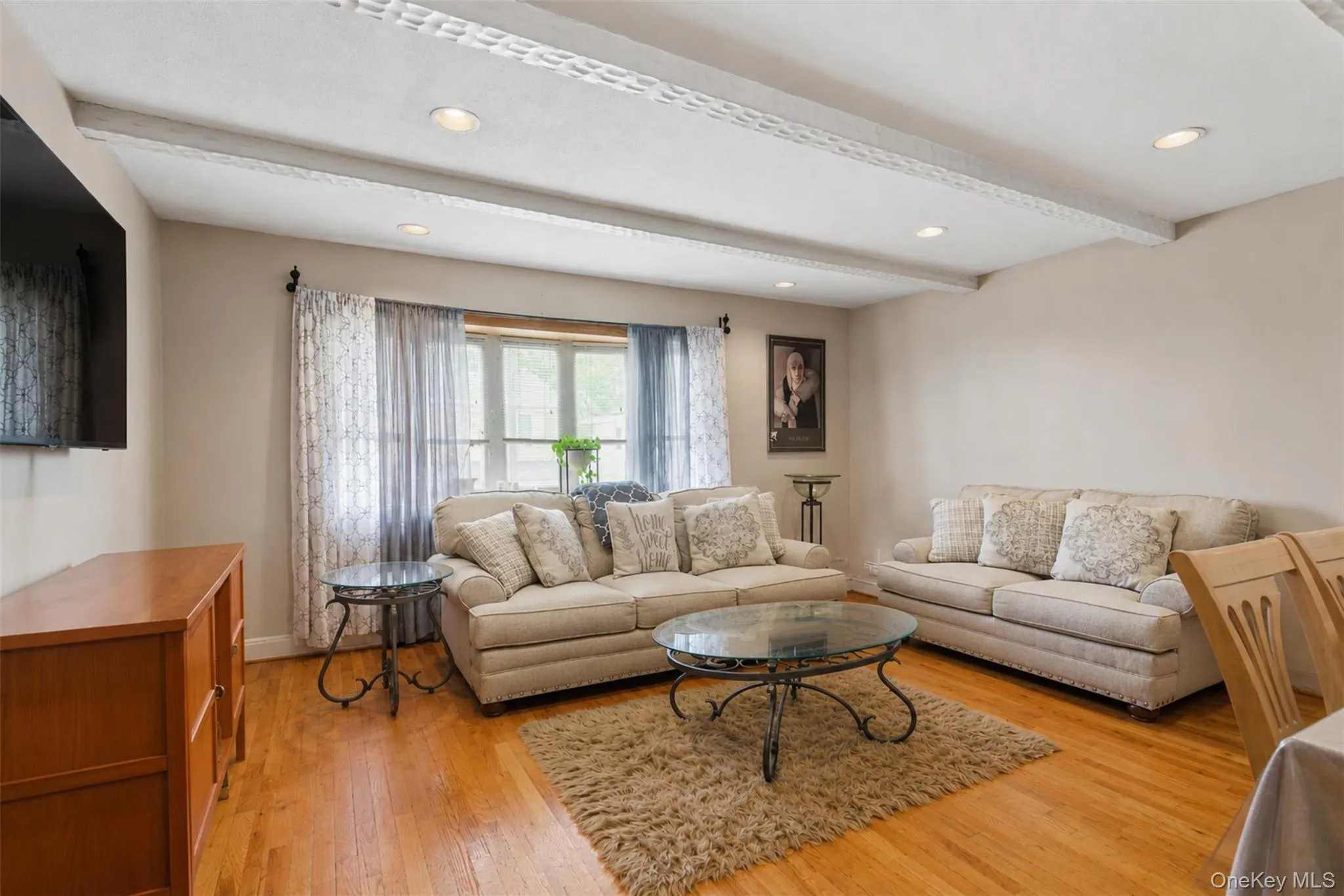 Living area featuring wood-finish flooring, recessed lighting, and exposed ceiling beams Living area featuring wood-finish flooring, recessed lighting, and exposed ceiling beams